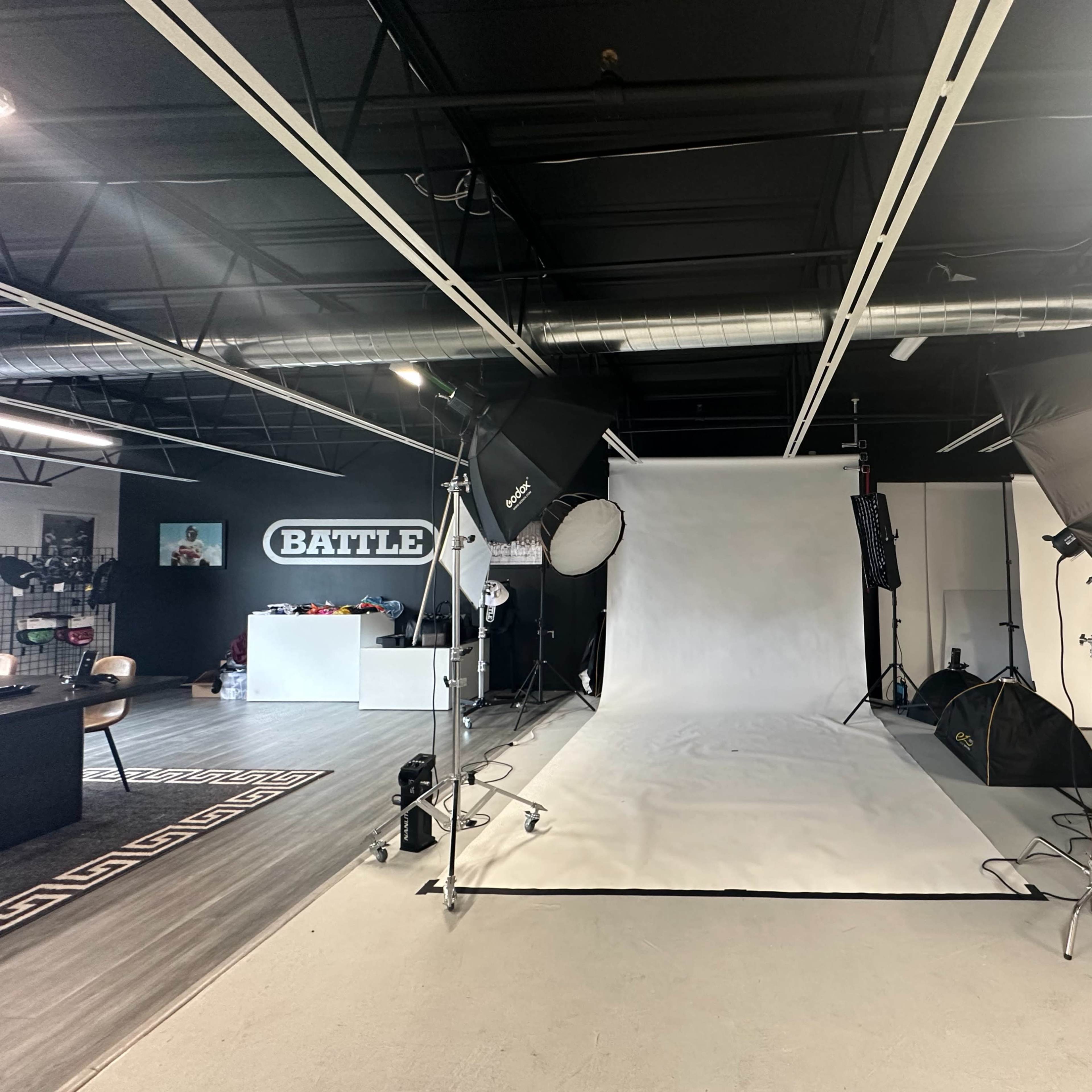 A photography studio with a white backdrop surrounded by lighting equipment and various studio props.