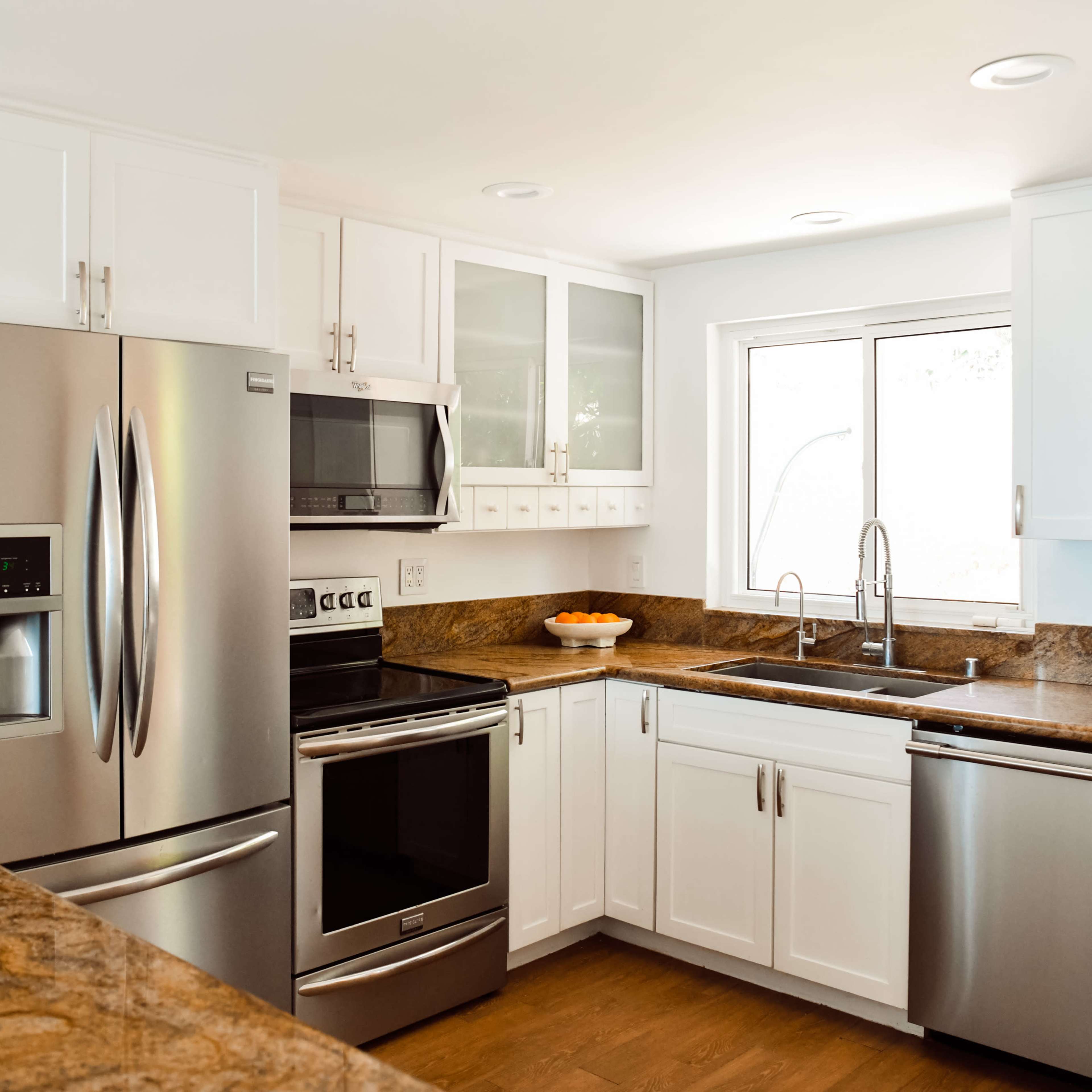 A modern kitchen with stainless steel appliances, white cabinetry, and granite countertops.