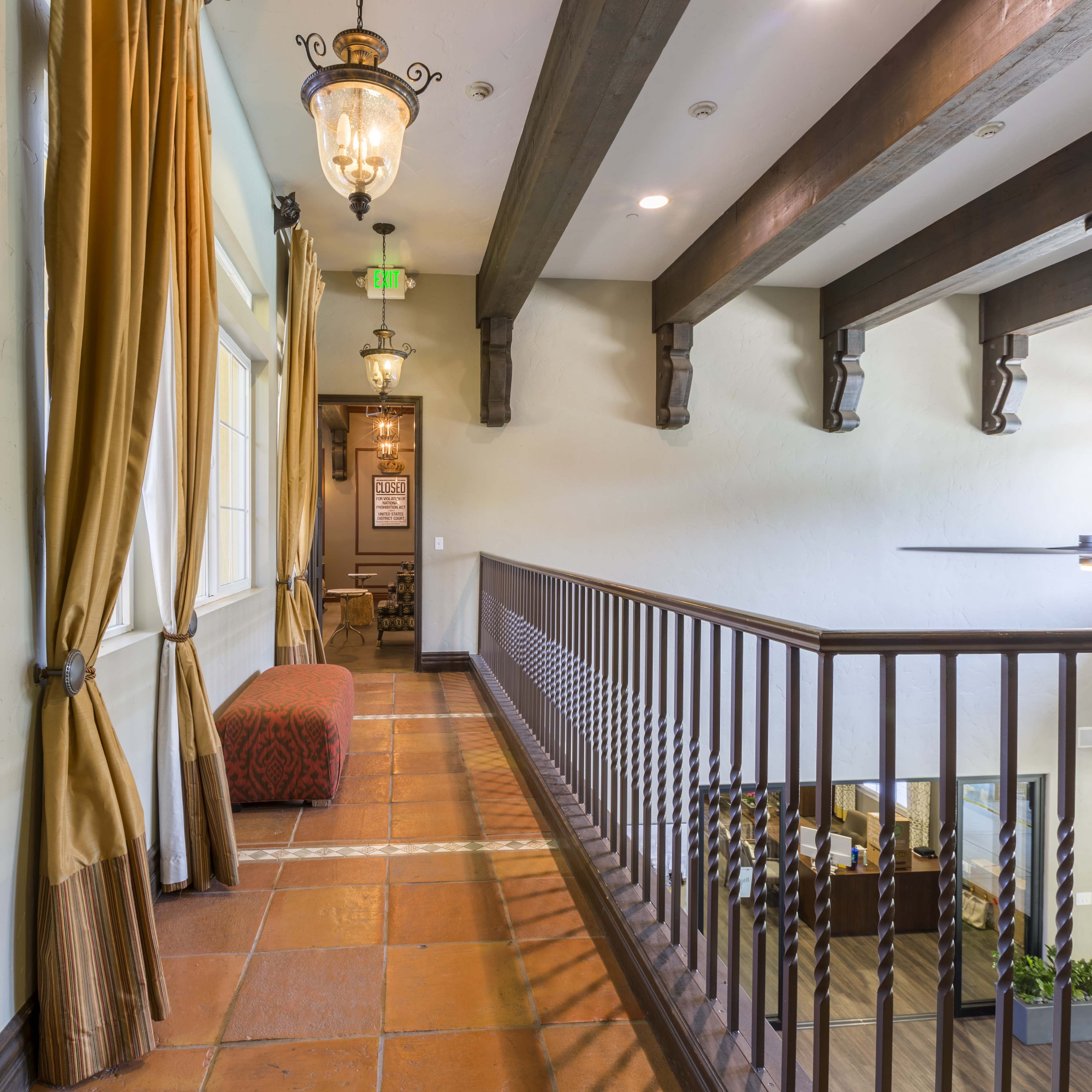 A hallway with wooden beams and decorative lights, leading to a seating area at the end.