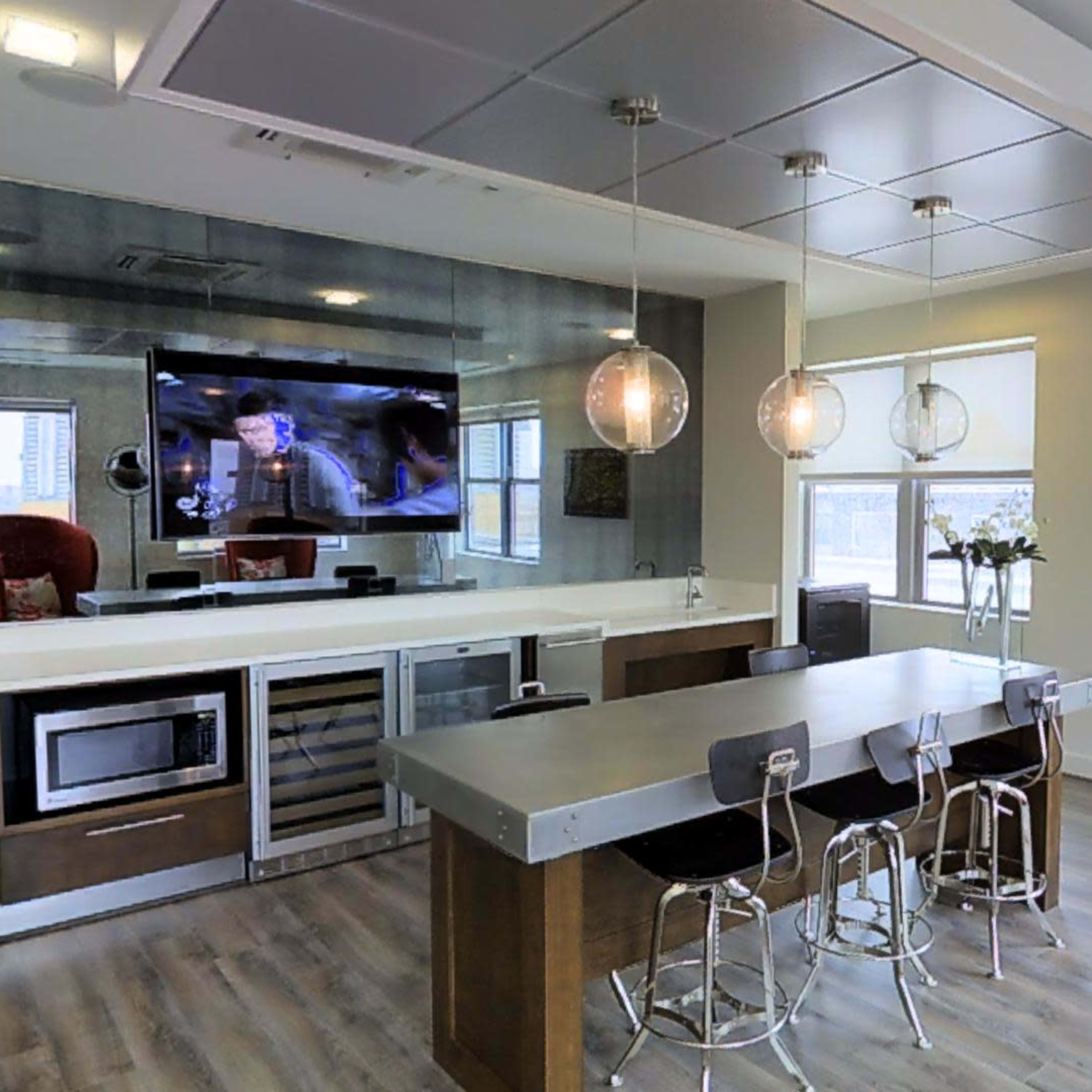 A modern kitchen with a large island, bar stools, and a television mounted on the wall.