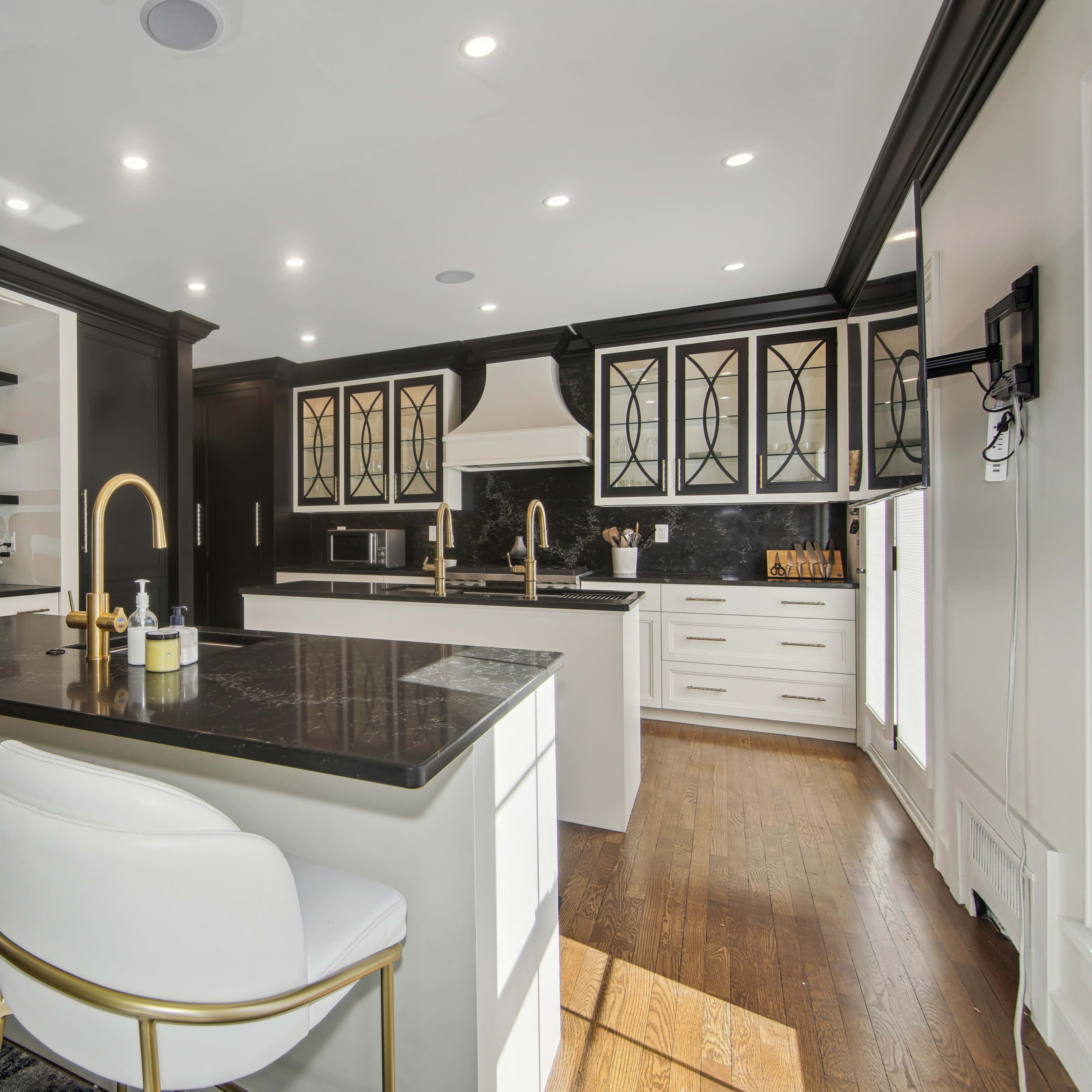 The kitchen features black cabinetry, a central island with white bar stools, and modern appliances against a contrasting black backsplash.