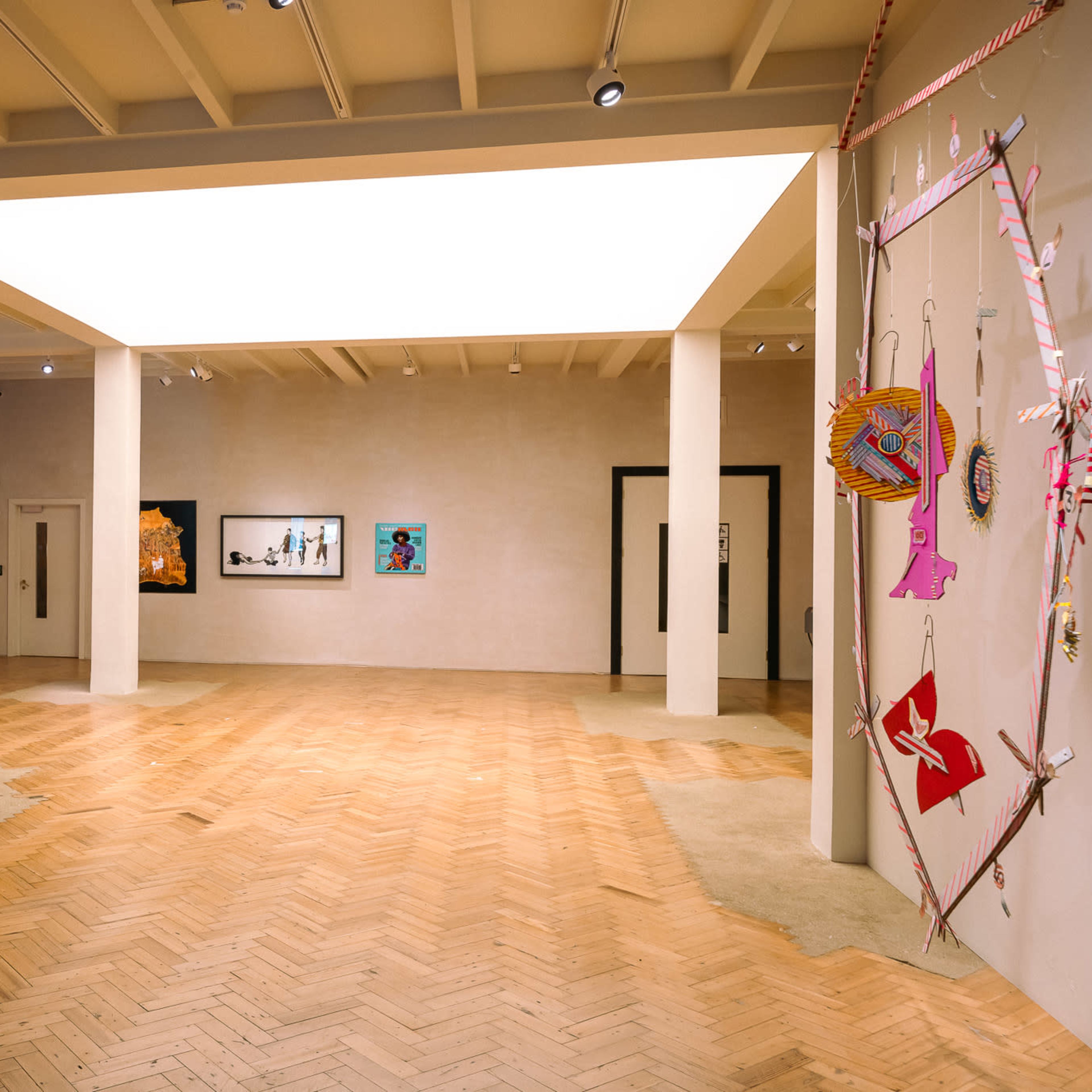 An art gallery featuring colorful artworks on the walls and a spacious wooden floor.