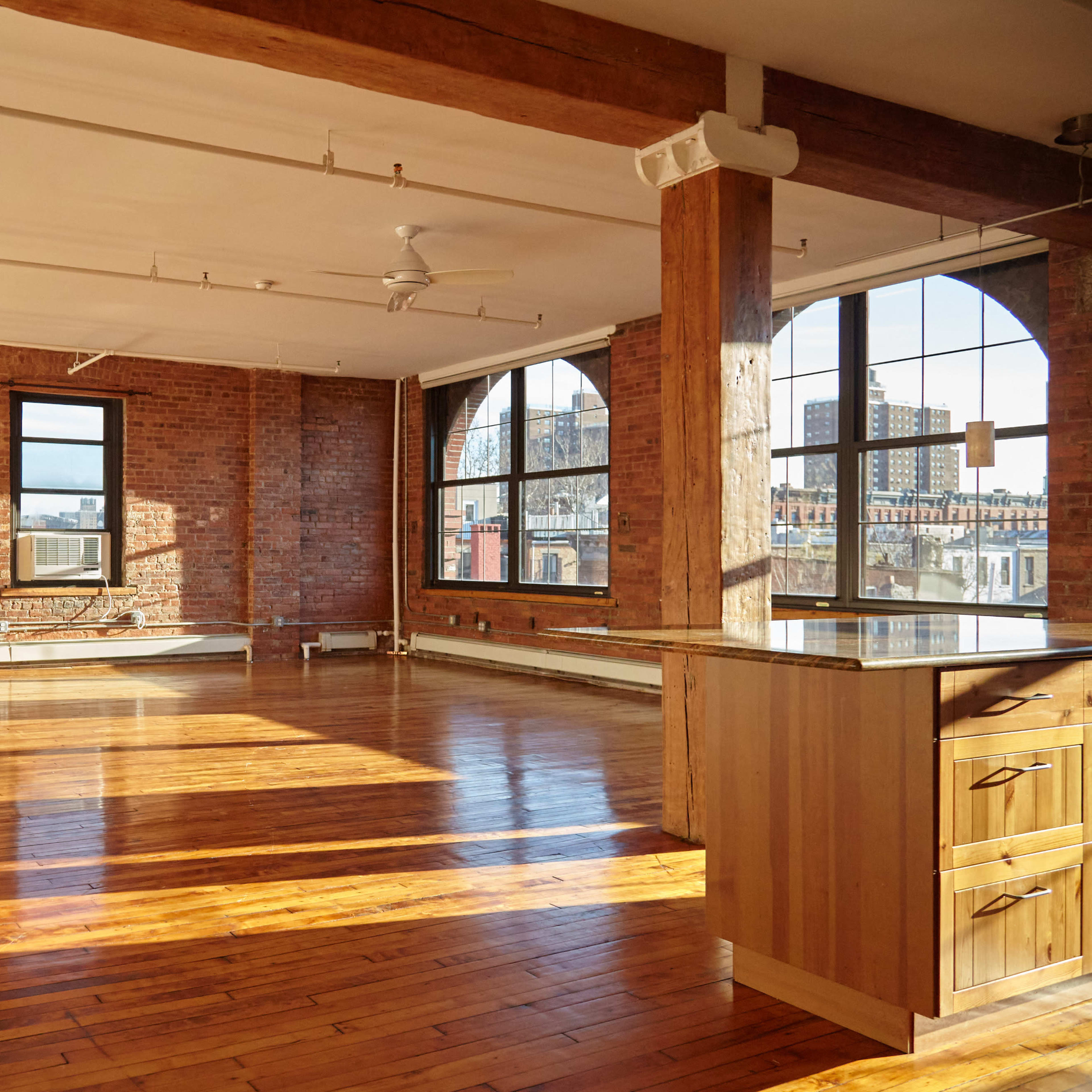 A spacious loft with wooden floors, exposed brick walls, and large windows providing natural light.