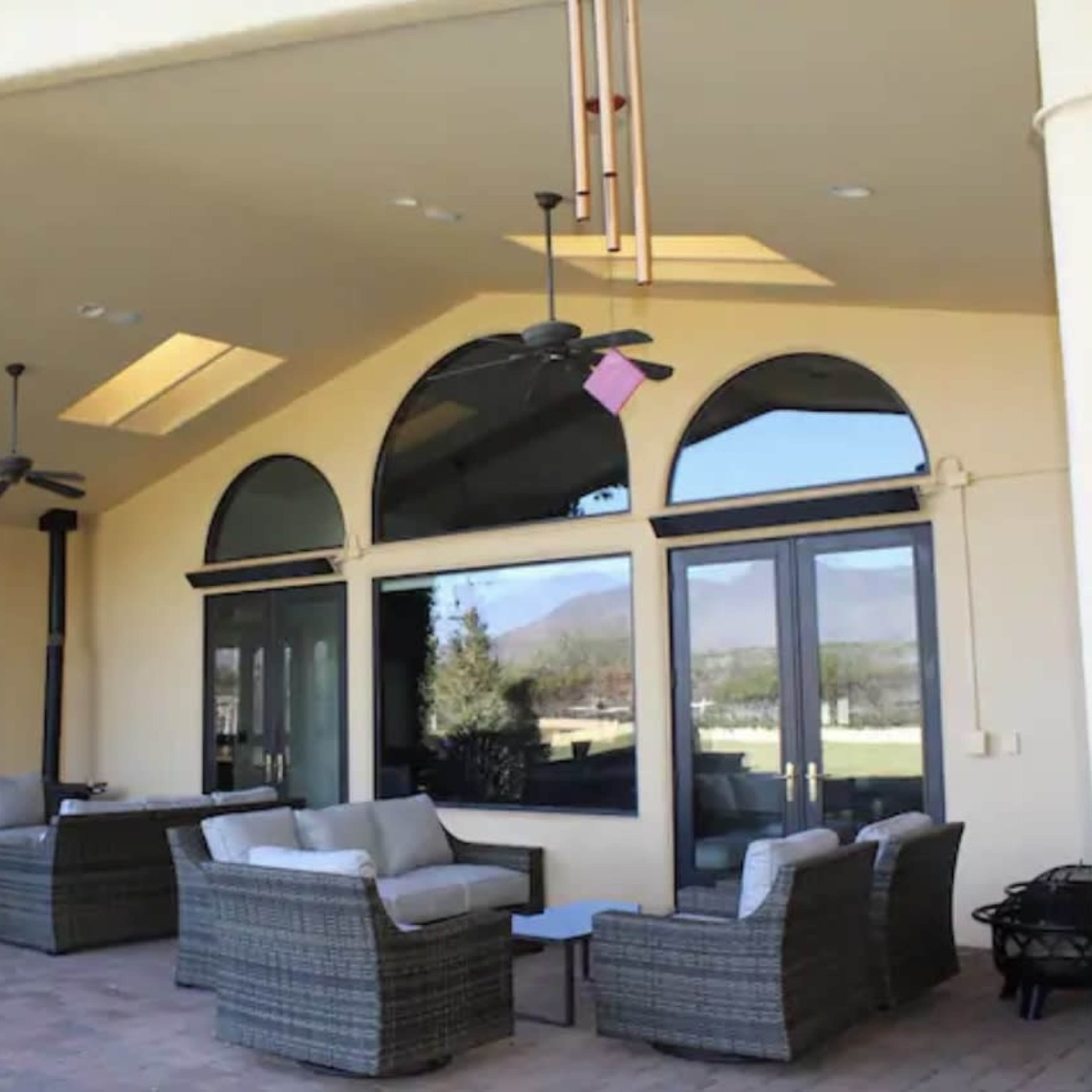A spacious outdoor patio area with comfortable seating arrangements and large arched windows.
