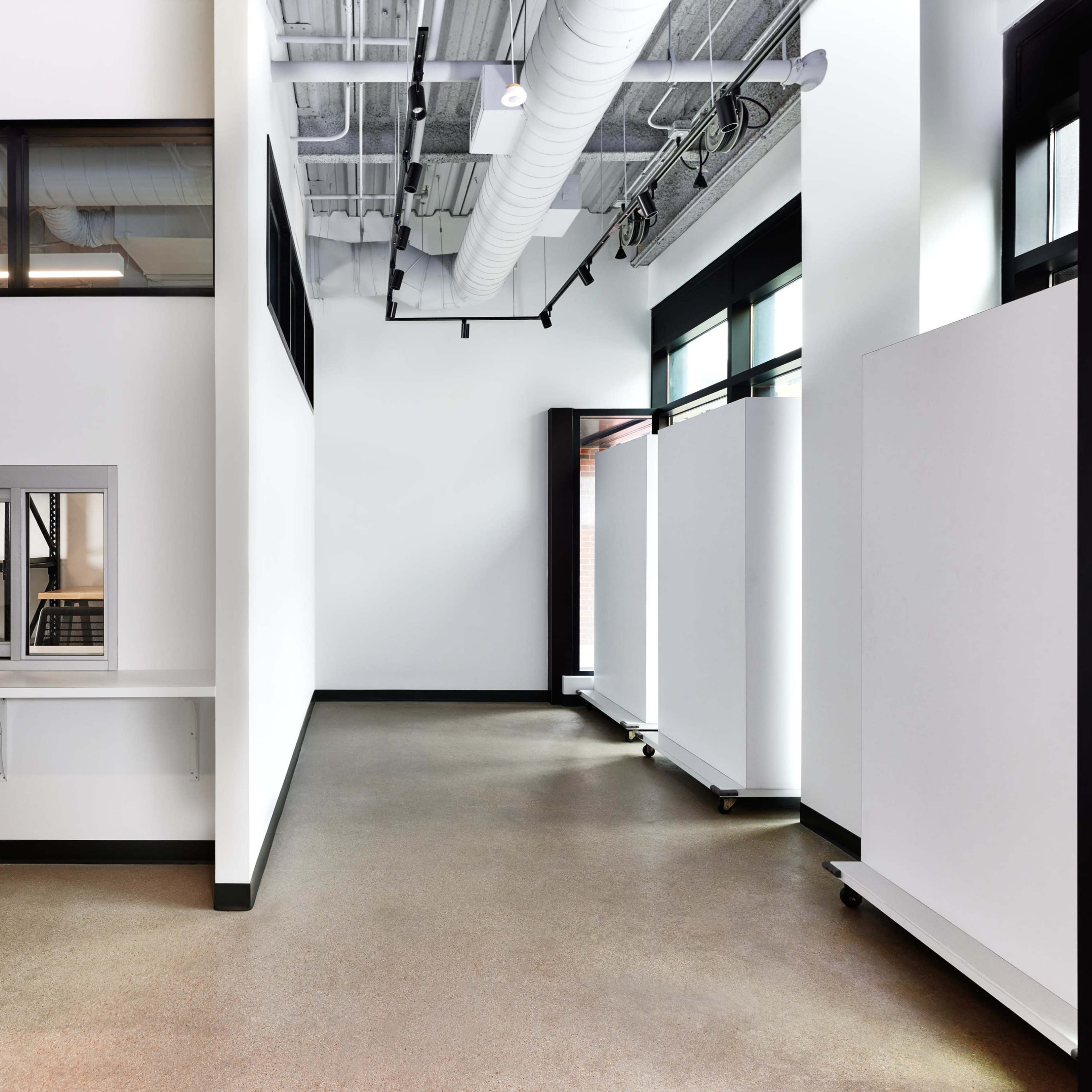 A spacious, modern interior with white walls, large windows, and a clean, uncluttered floor layout.