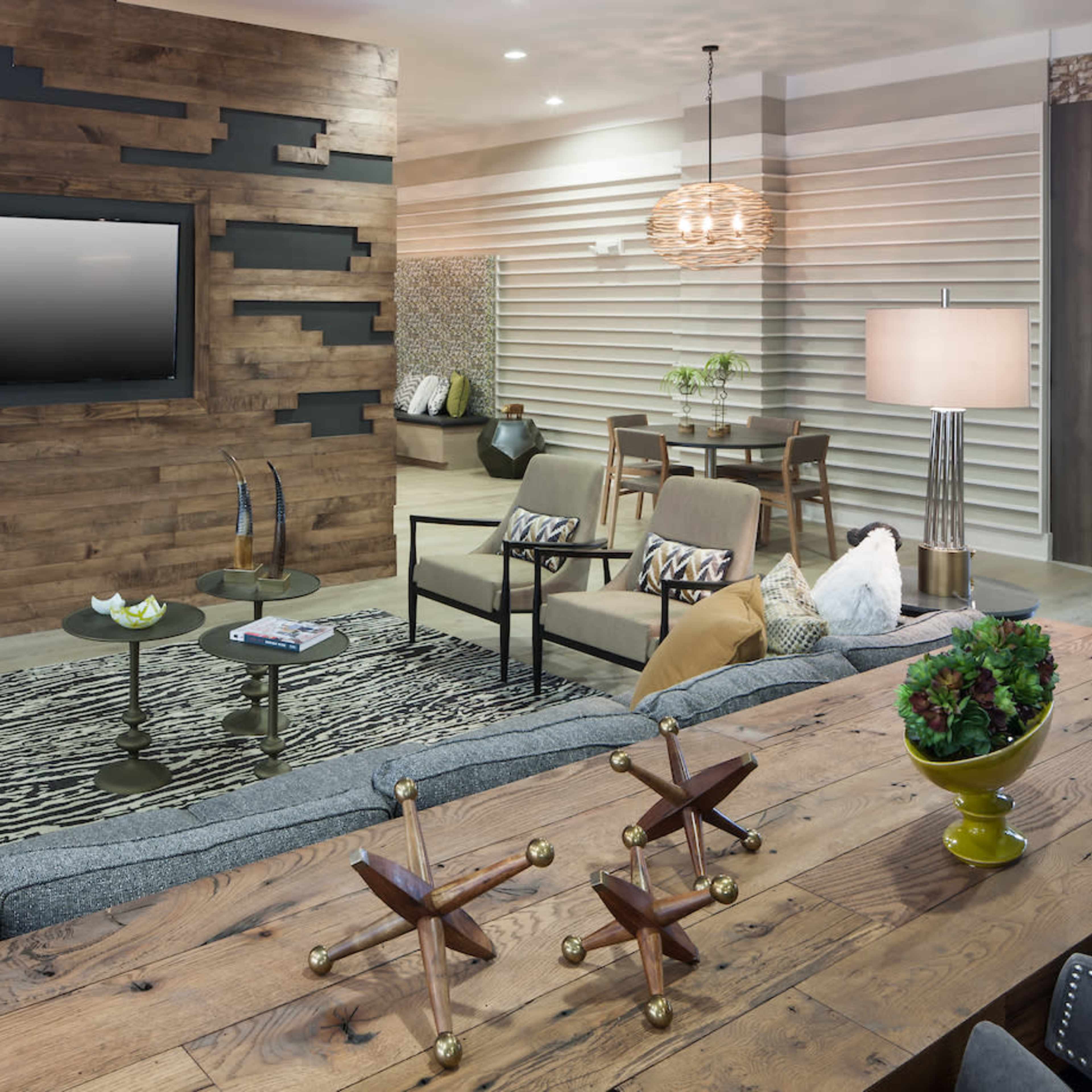 A modern living room features a textured wood-paneled wall, a large gray sectional sofa, and stylish furniture arranged around a central coffee table.