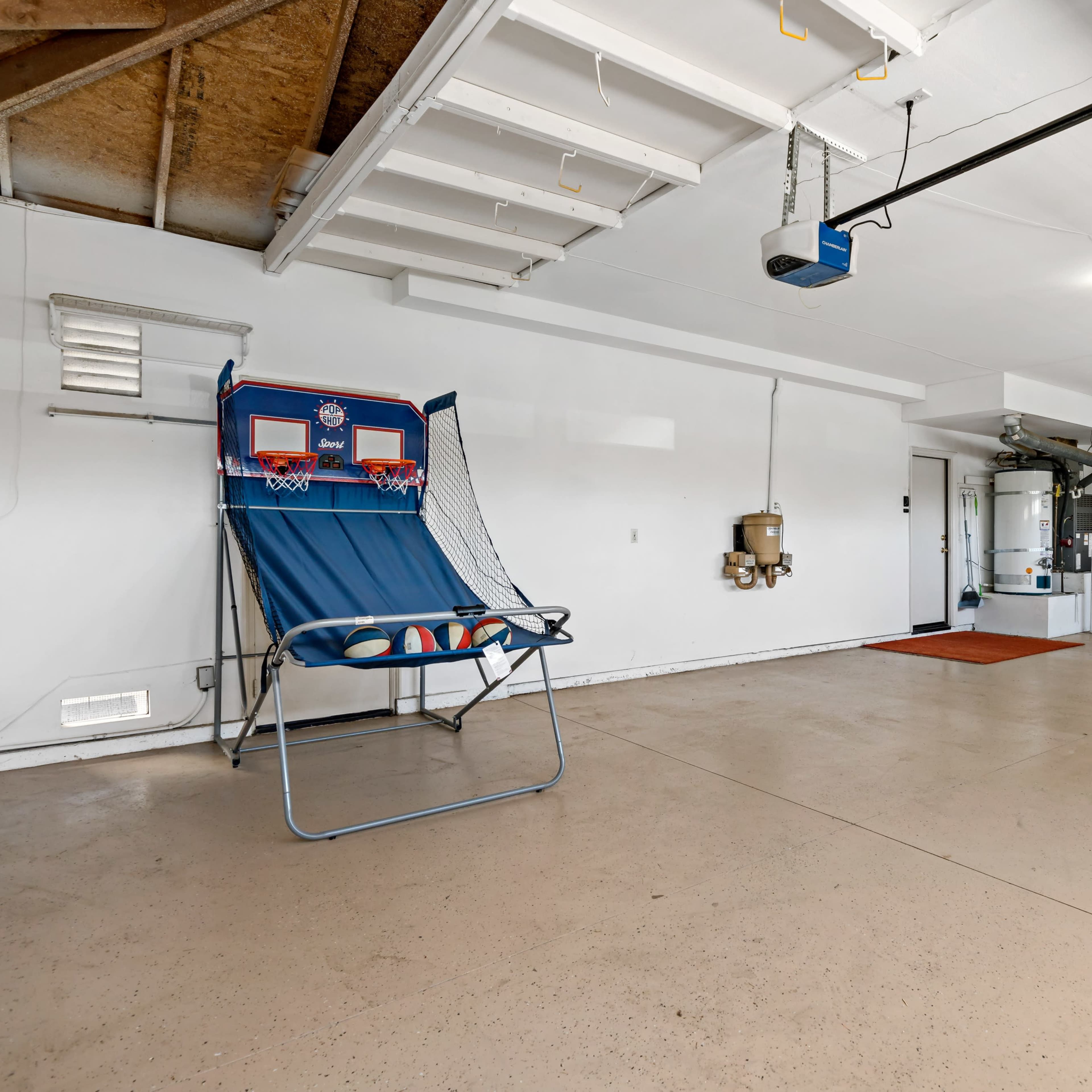 A spacious garage with a basketball hoop set up at one end and cabinets along the walls.