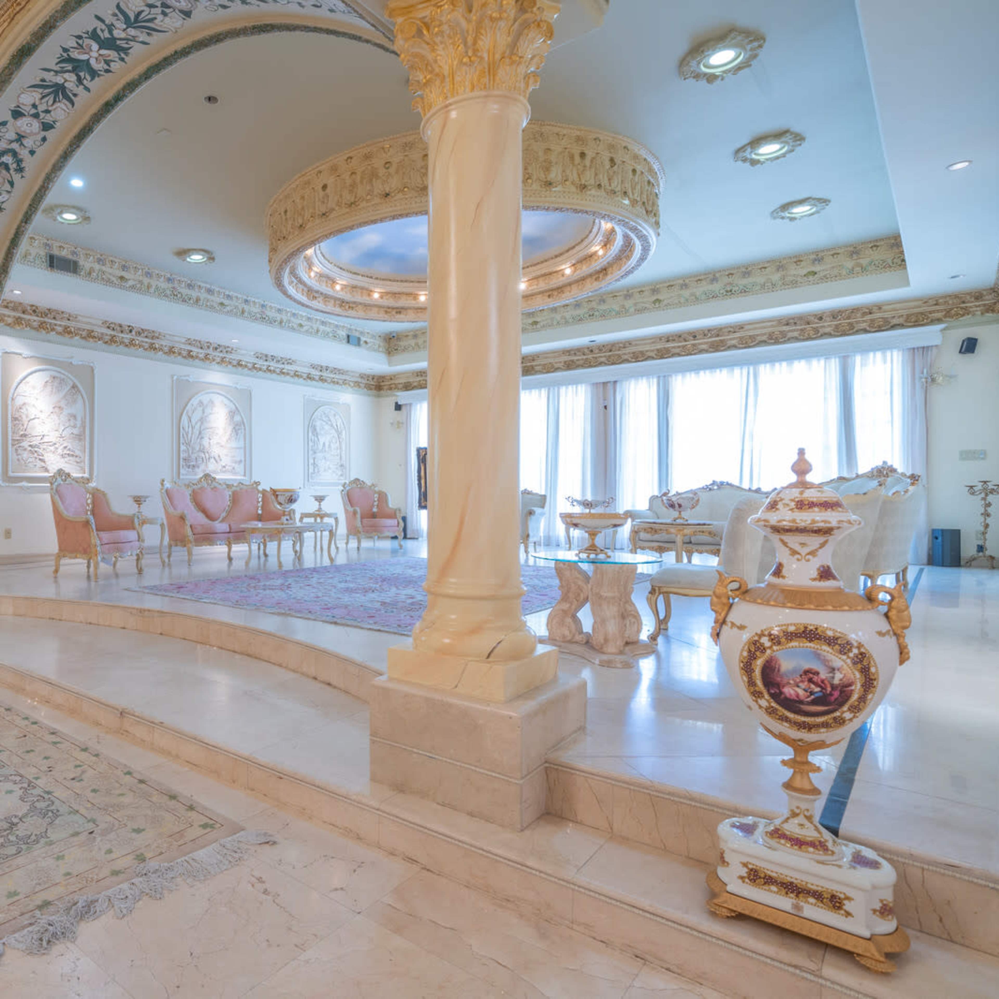 A spacious, elegantly designed living room with ornate architectural details, a decorative ceiling, and luxurious furnishings.