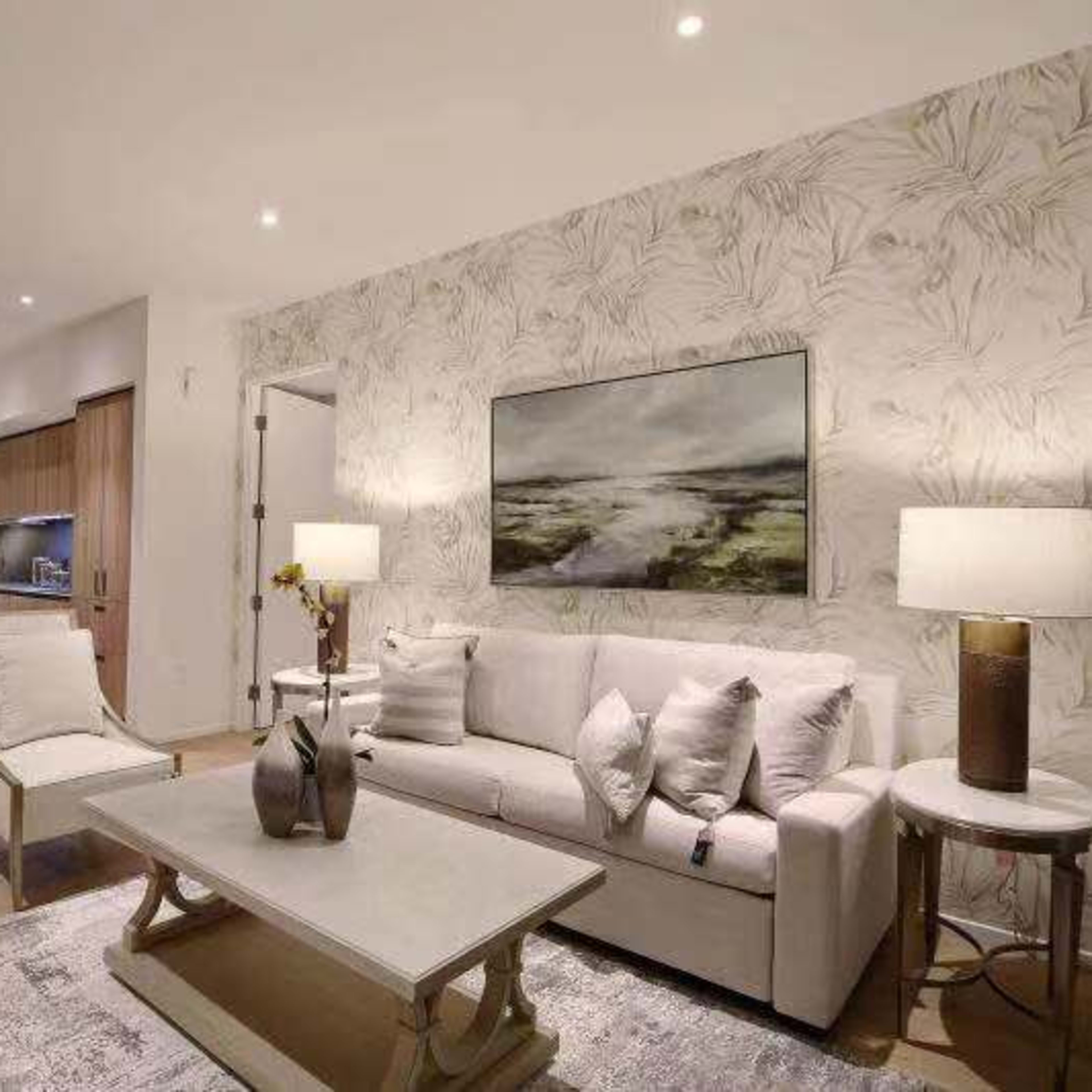 A modern living room featuring a white sofa, a wooden coffee table, and a decorative wall with floral wallpaper.