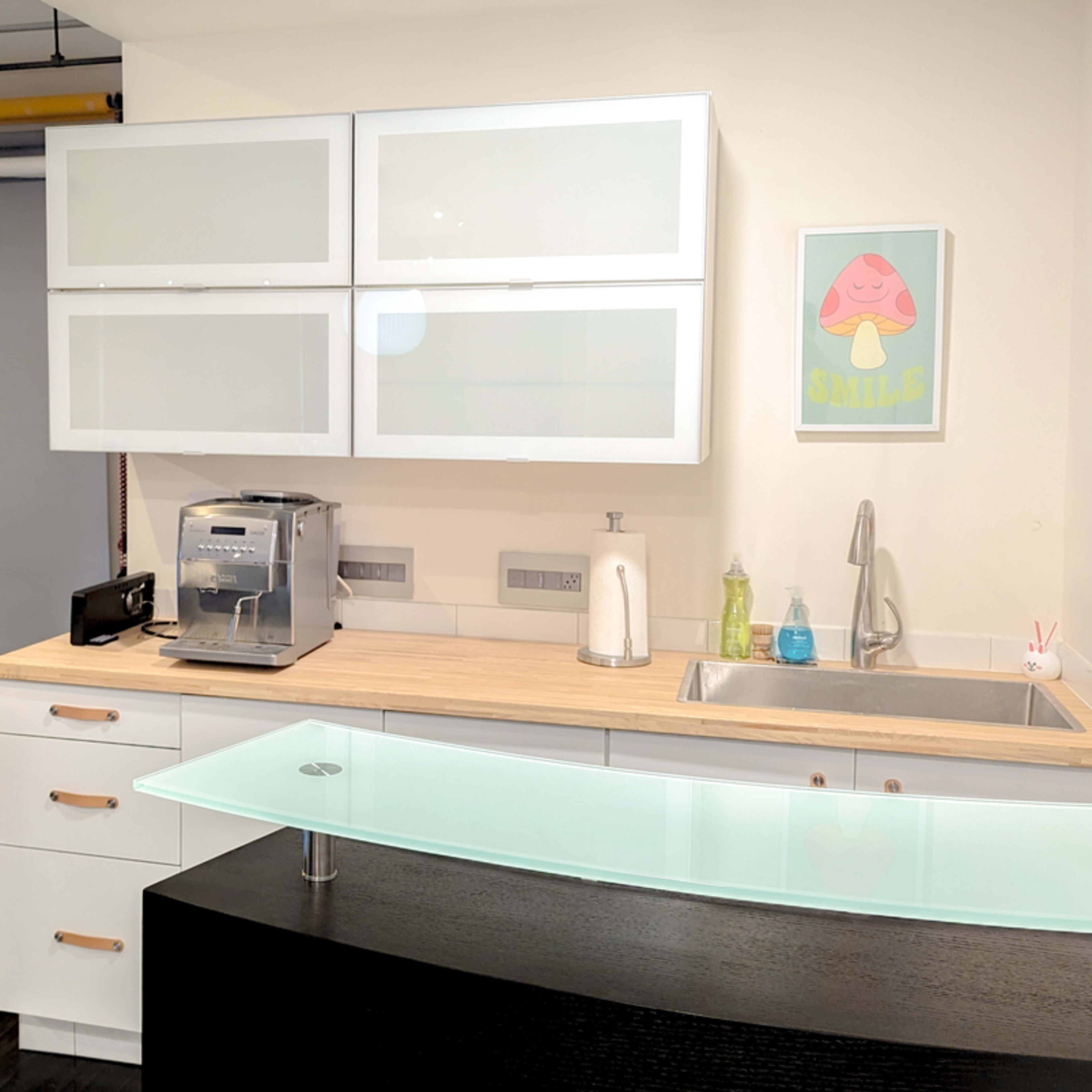 A modern kitchen area with a coffee machine and a sleek counter, adjacent to a photography studio backdrop.