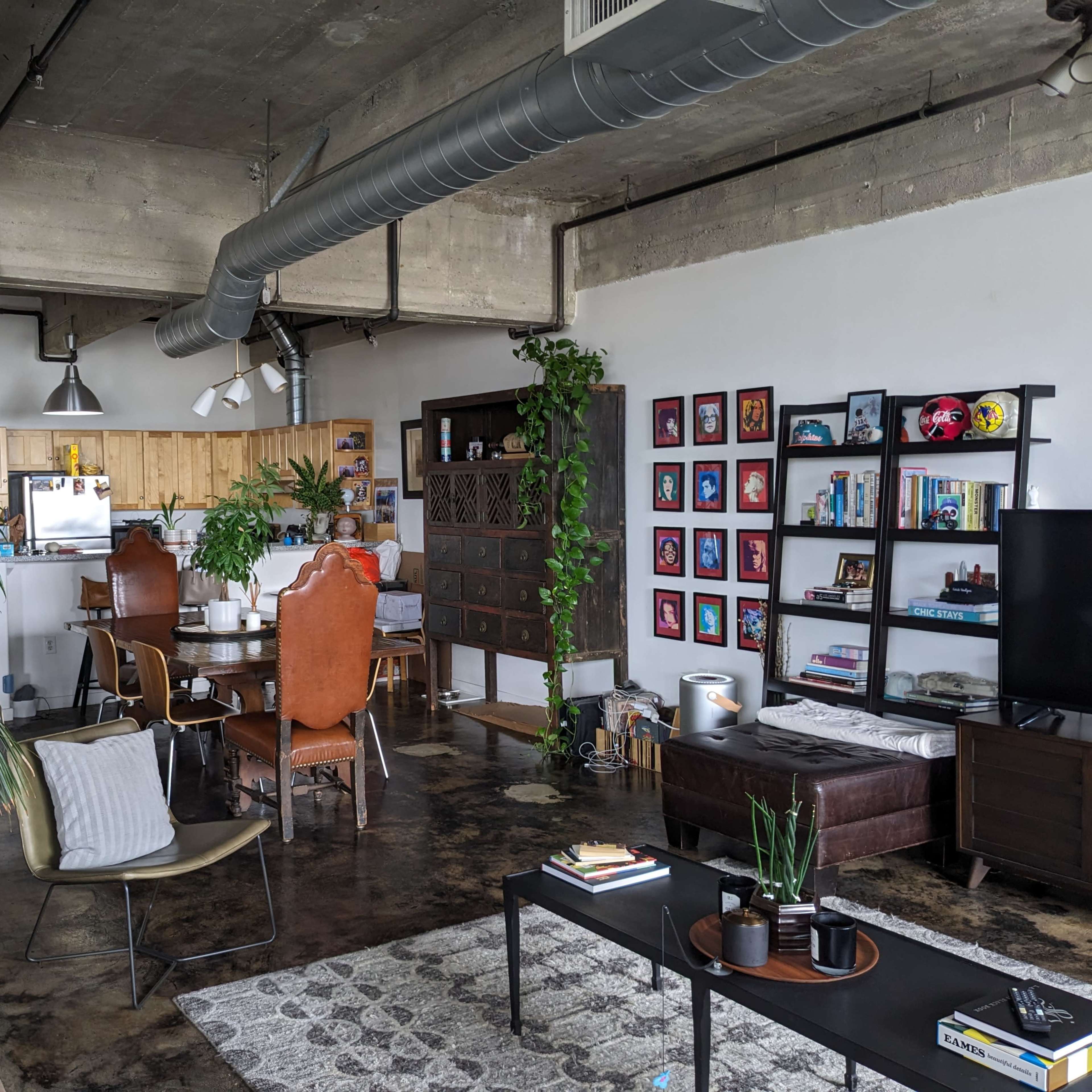 A modern industrial-style apartment with an open layout featuring a living area, dining space, and kitchen.