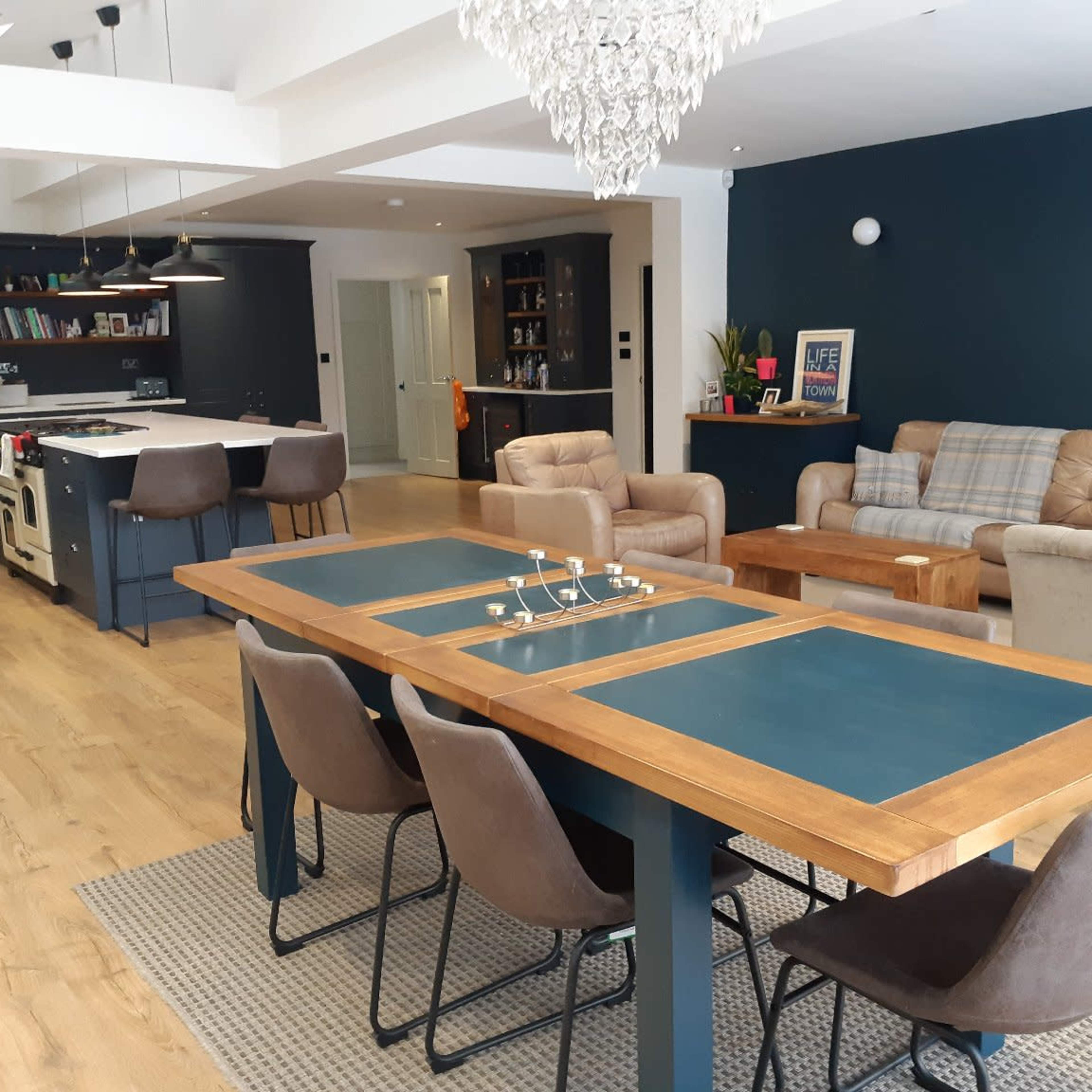 A modern open-concept living space featuring a dining area with a large table, comfortable seating, and an adjoining kitchen.