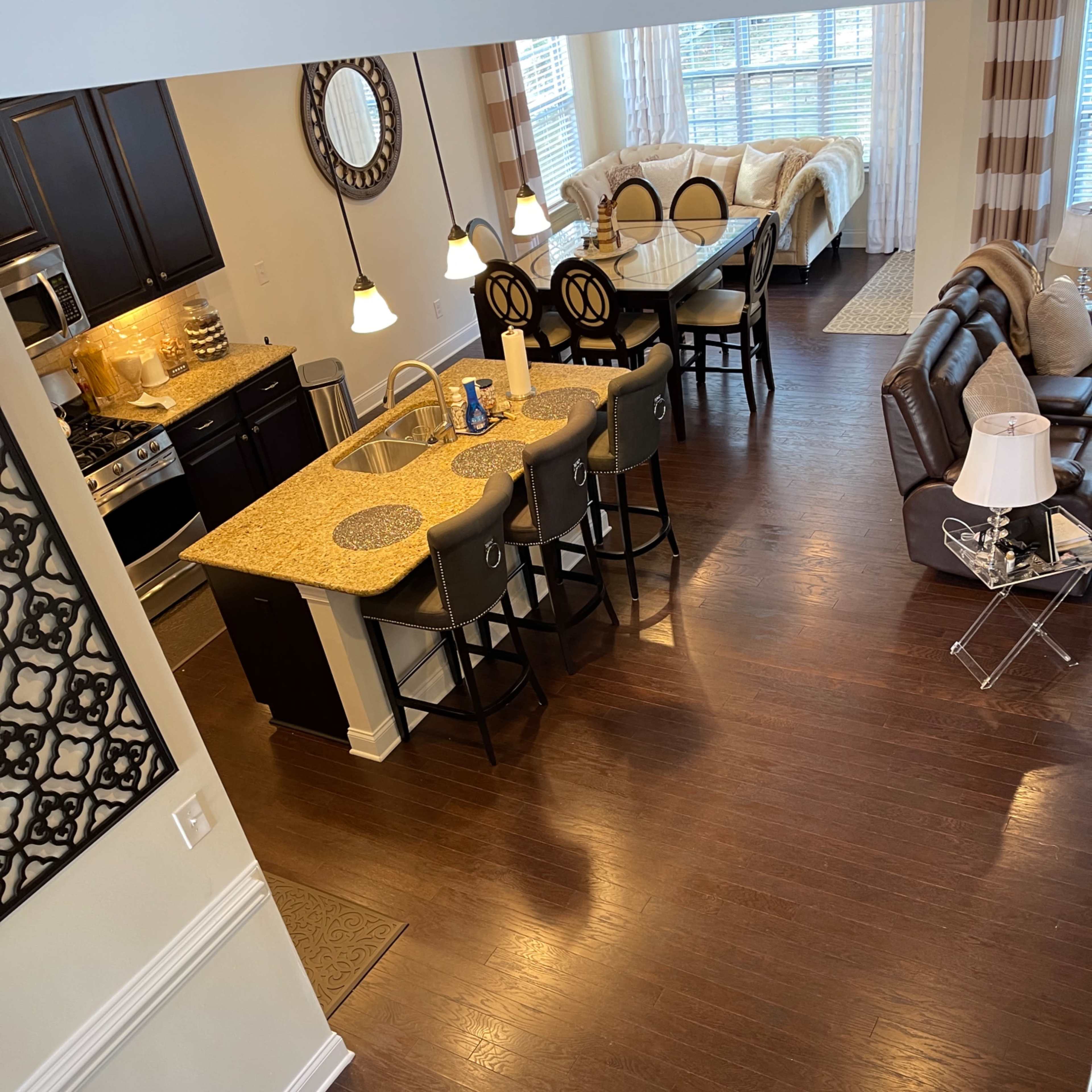 An open-concept living space featuring a kitchen with a granite island, a dining area with barstools, and a cozy seating area with a sofa and decorative pillows.