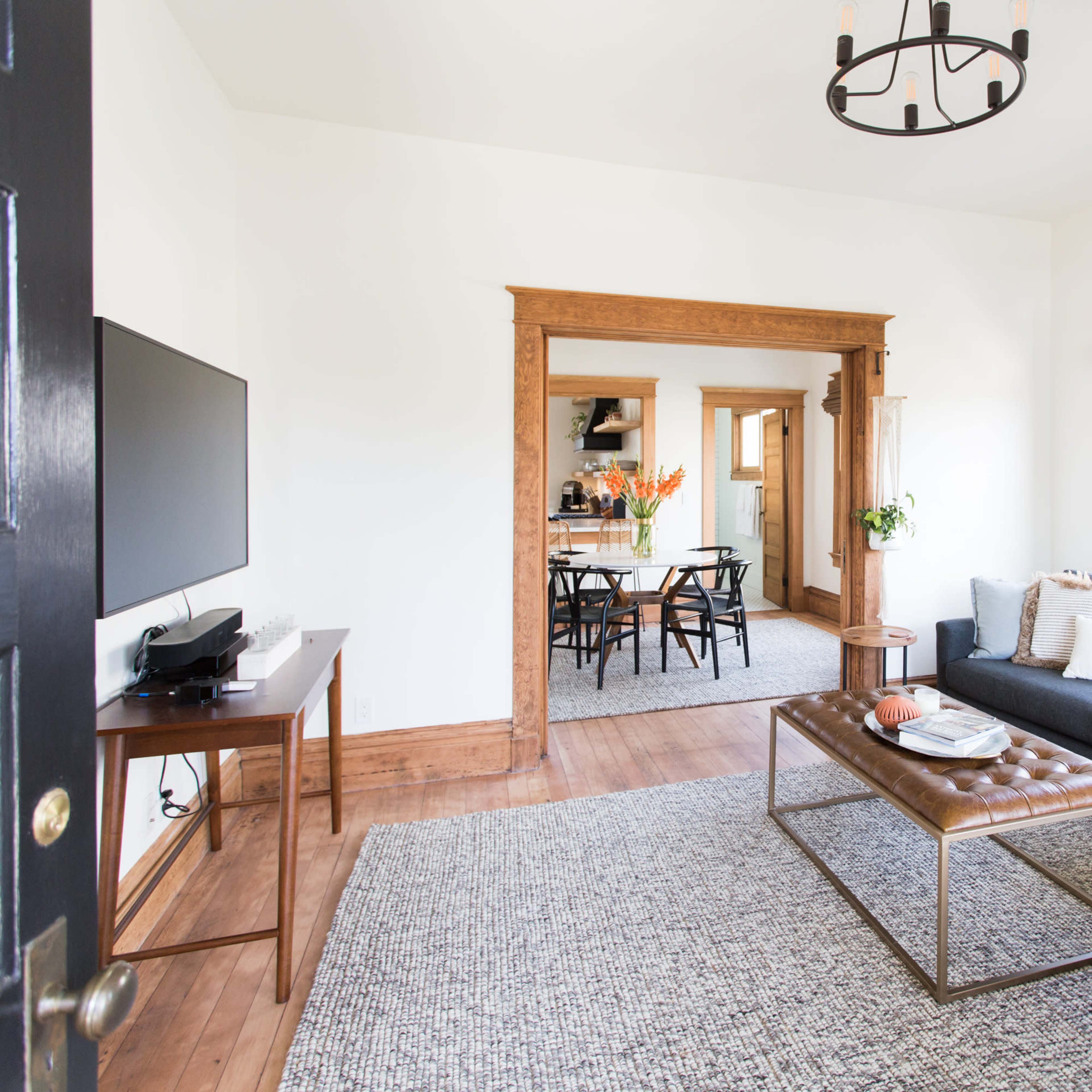 A living room with a gray sofa, a coffee table, and a view into a dining area through an archway.