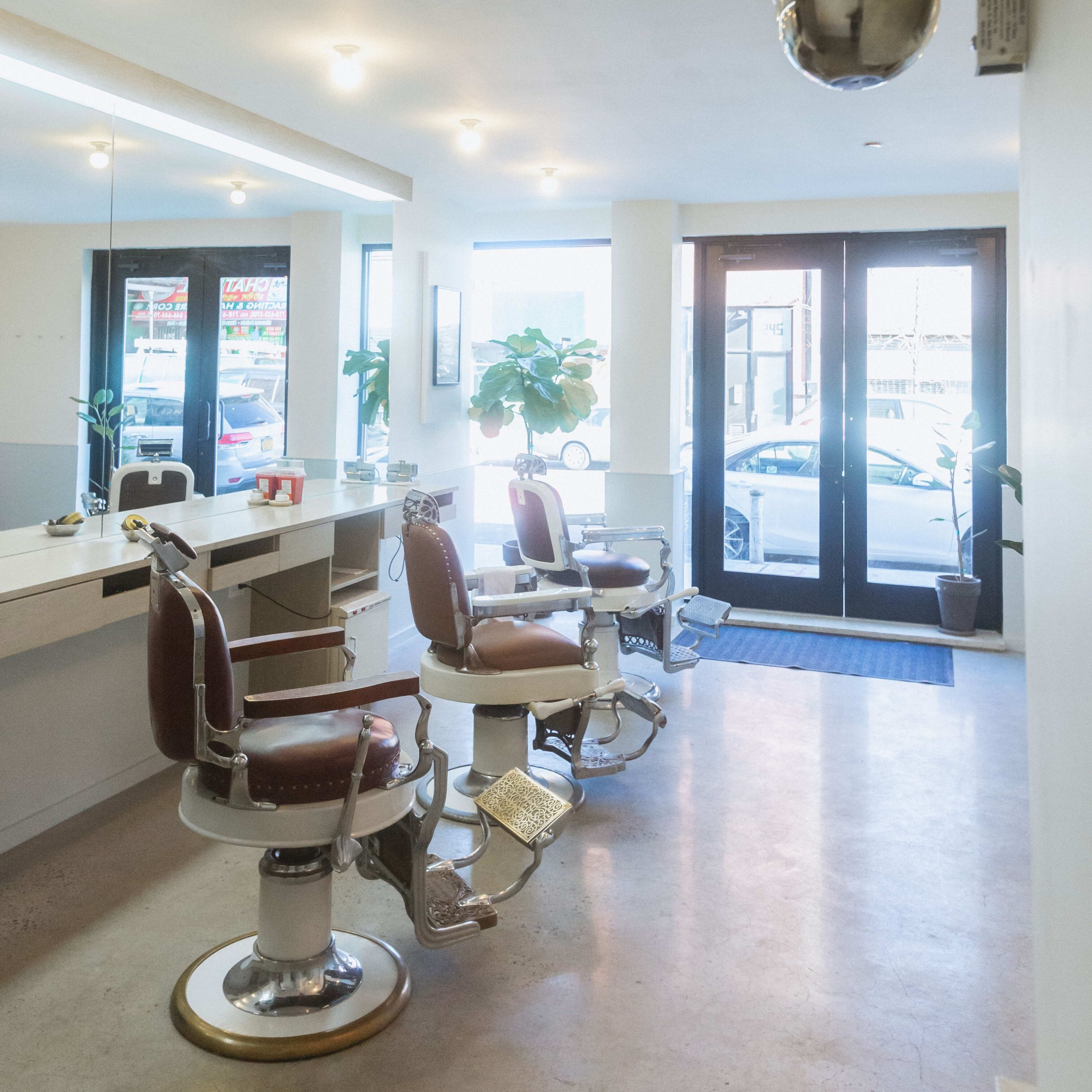A clean barbershop interior with two barber chairs, a mirror, and a classic barber pole.