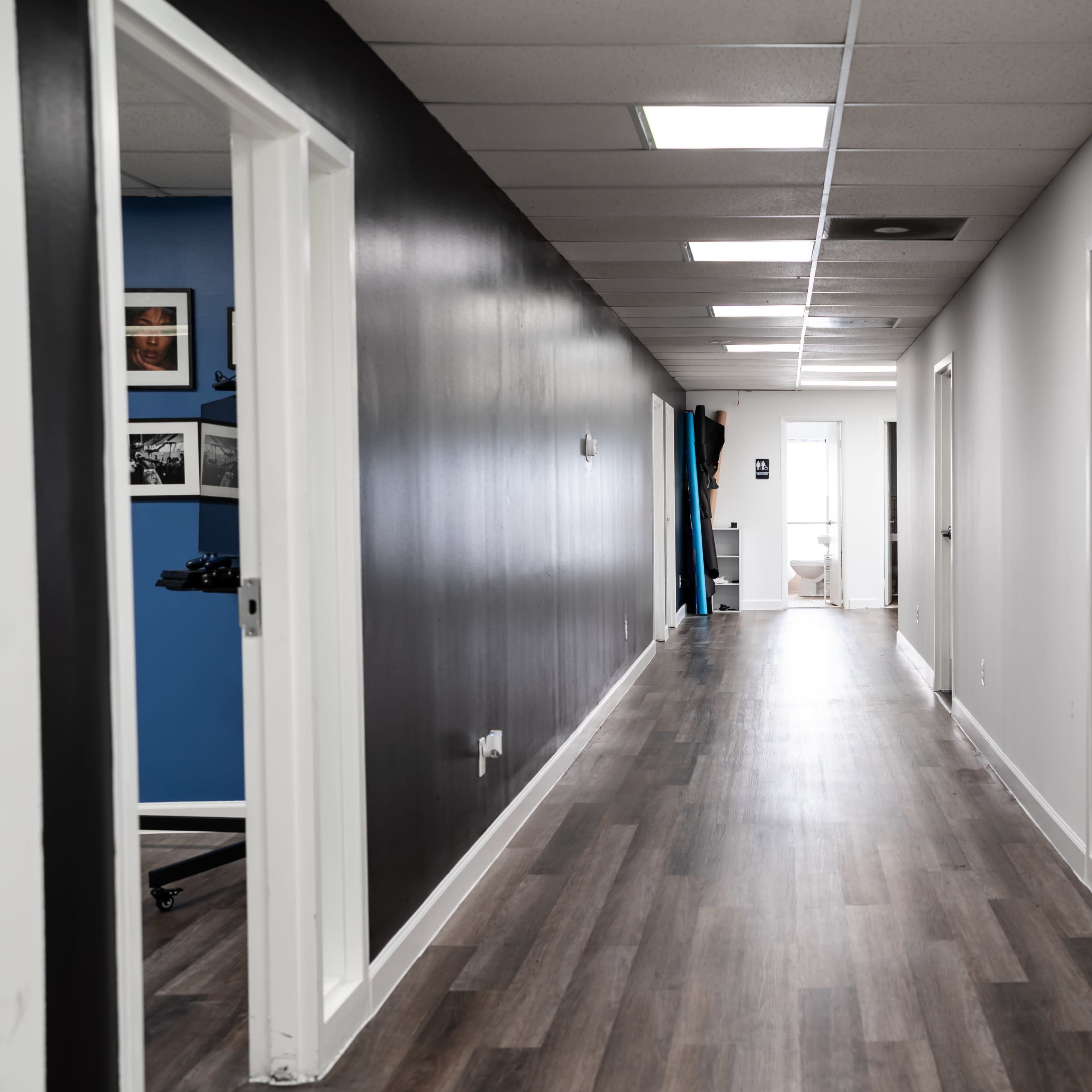 A long, narrow hallway with white and black painted walls and several closed doors on either side.