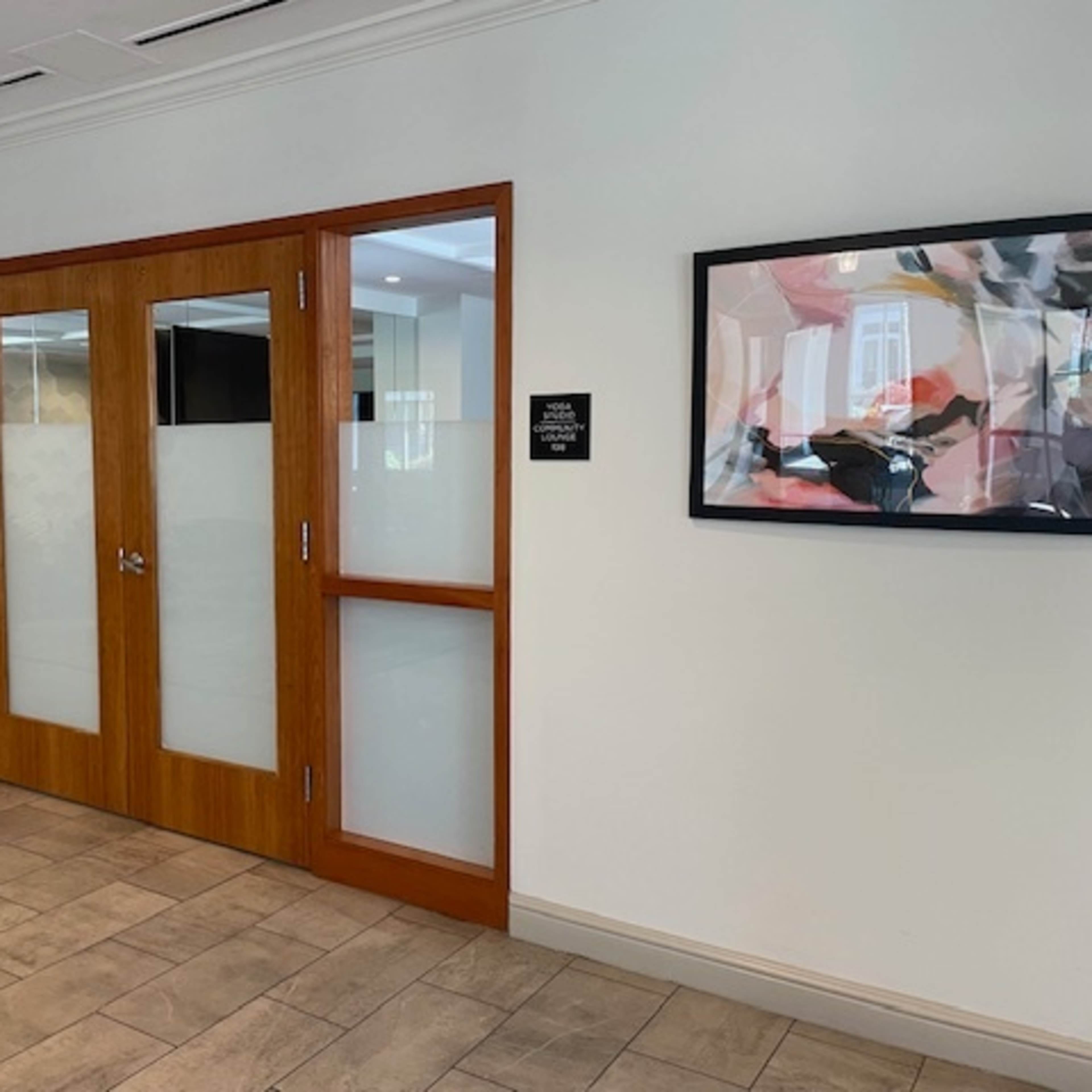 A wooden door with large glass panels, leading to a room, set within a modern interior hallway.