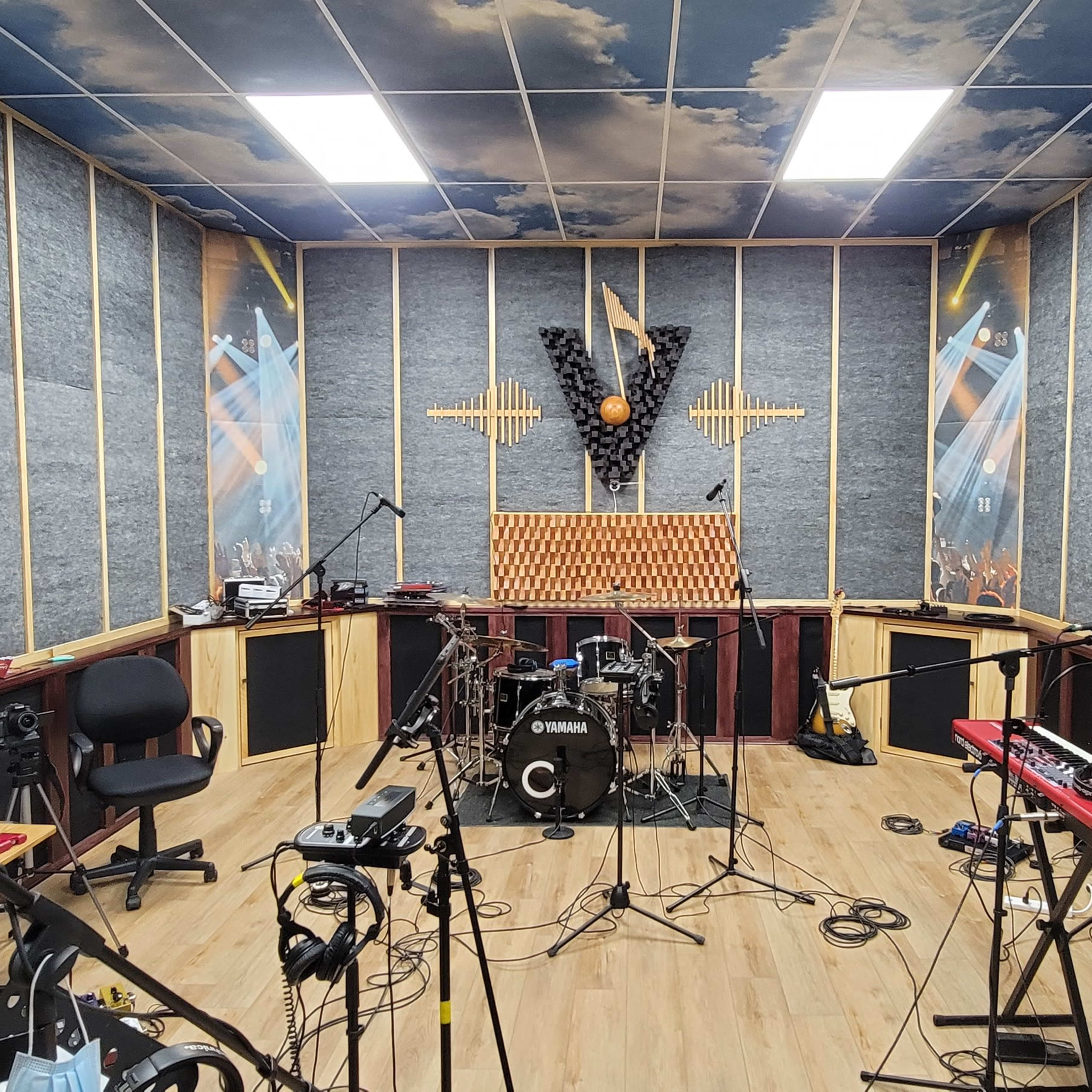 A soundproof music studio featuring various instruments, microphones, and acoustic paneling on the walls.