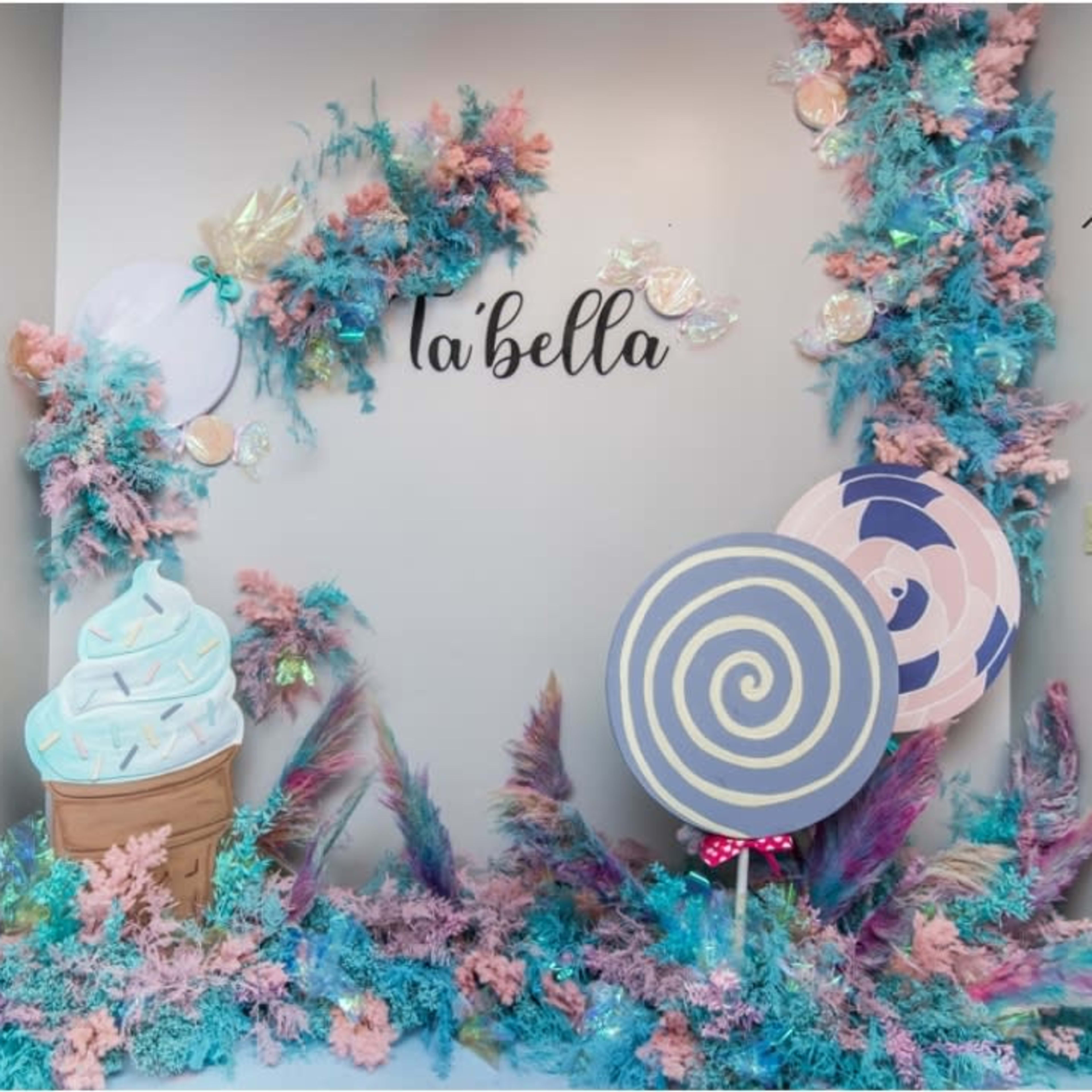 A decorative backdrop featuring pastel-colored ice cream cones, large lollipops, and colorful foliage for a themed event.