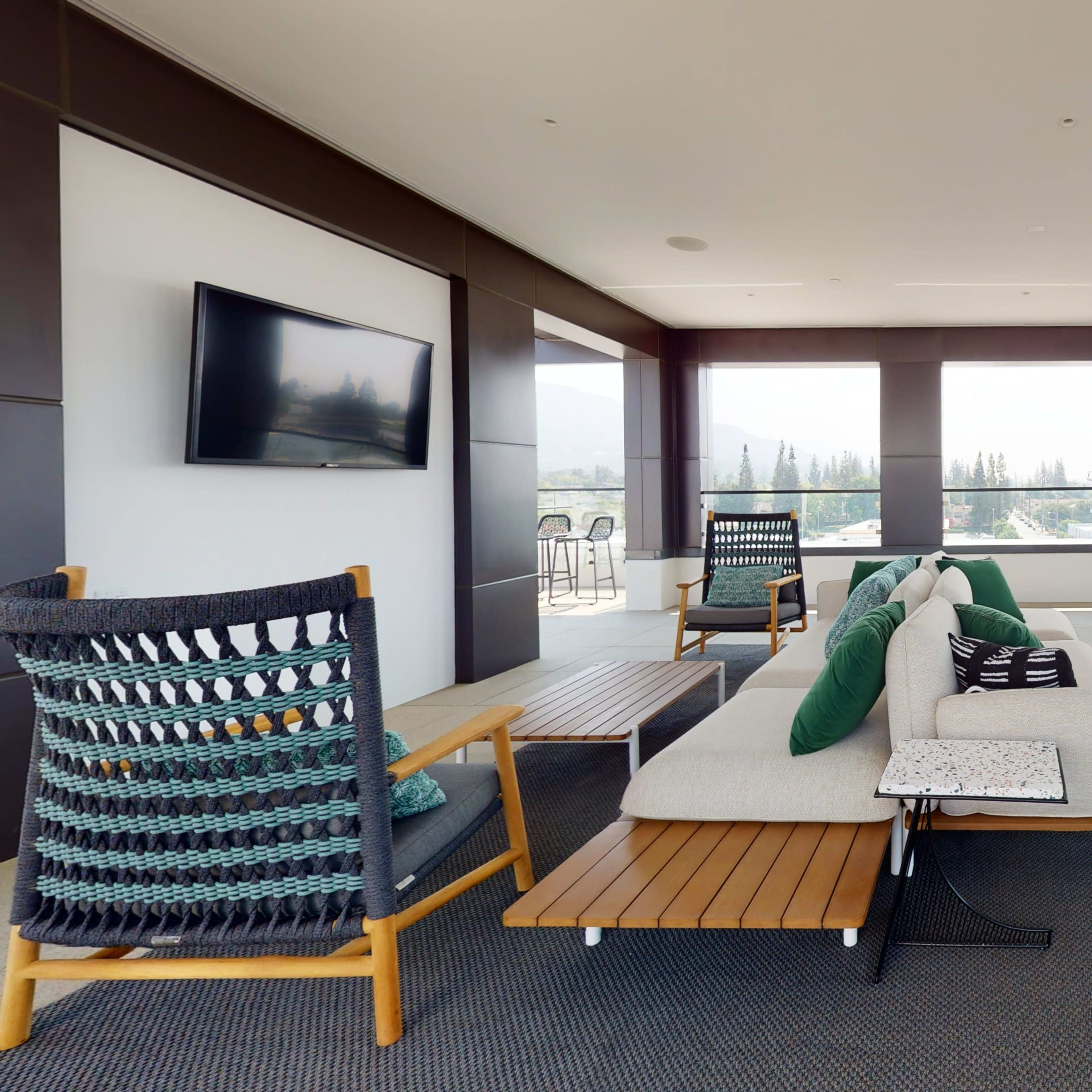 A modern indoor lounge with a pool table, comfortable seating area, and large windows overlooking a scenic view.