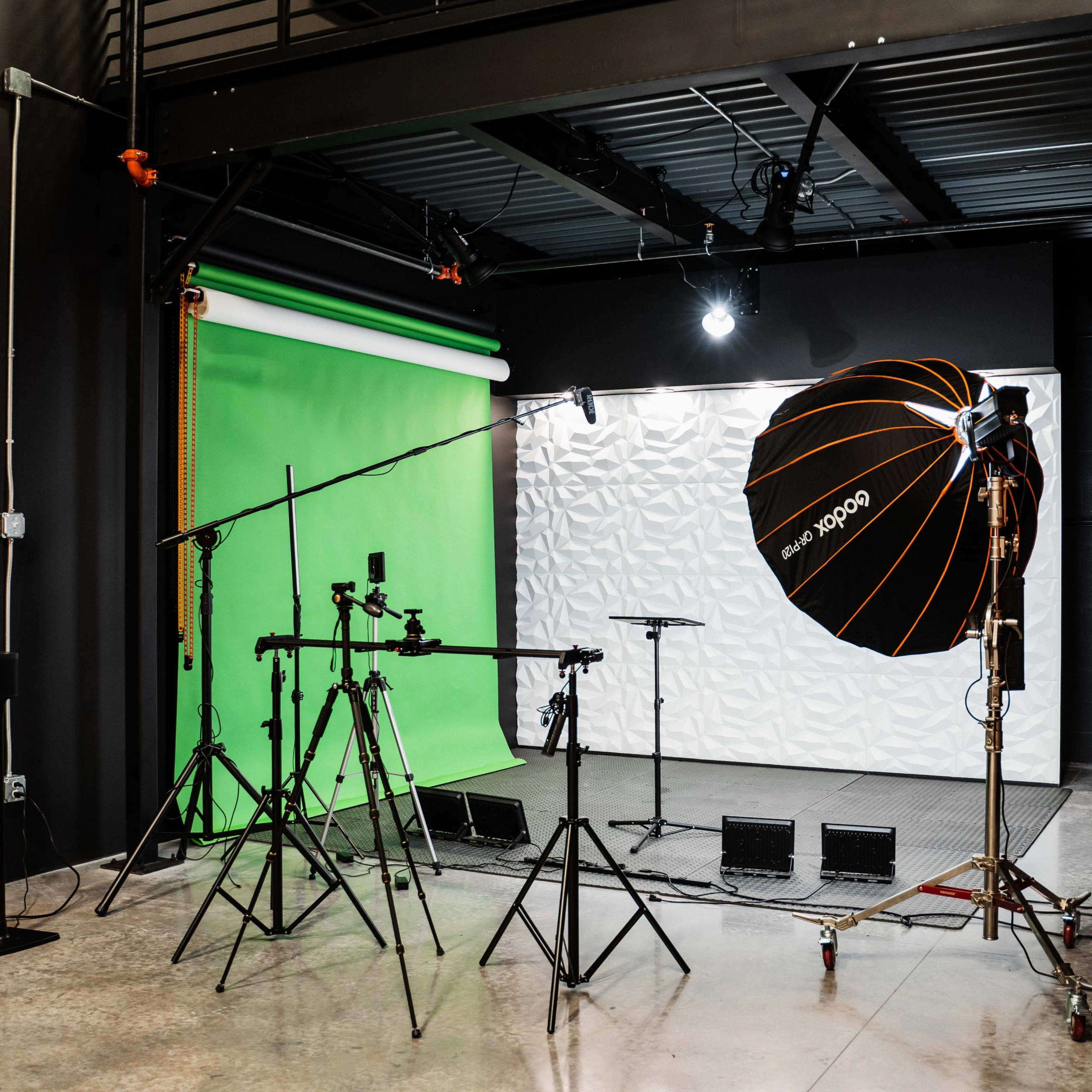 A photography studio equipped with green and textured white backdrops, lighting equipment, and tripods.
