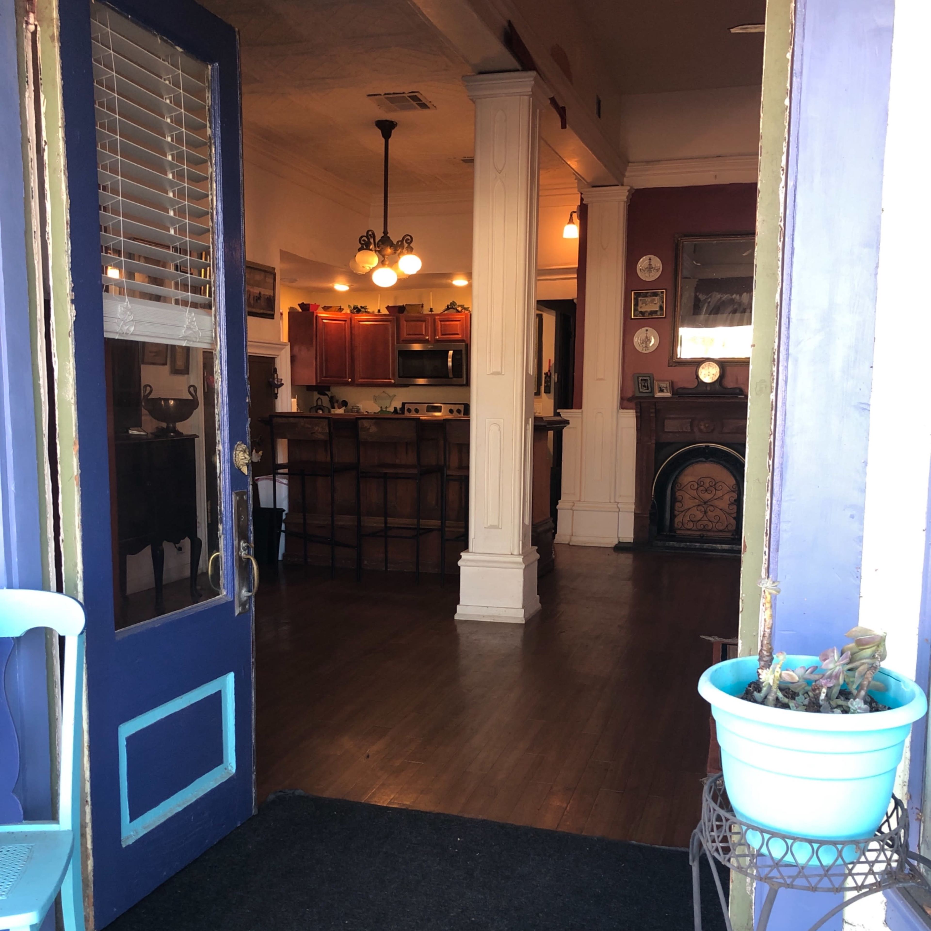 A view through a blue door leads to a cozy interior with a kitchen and dining area visible in the background.