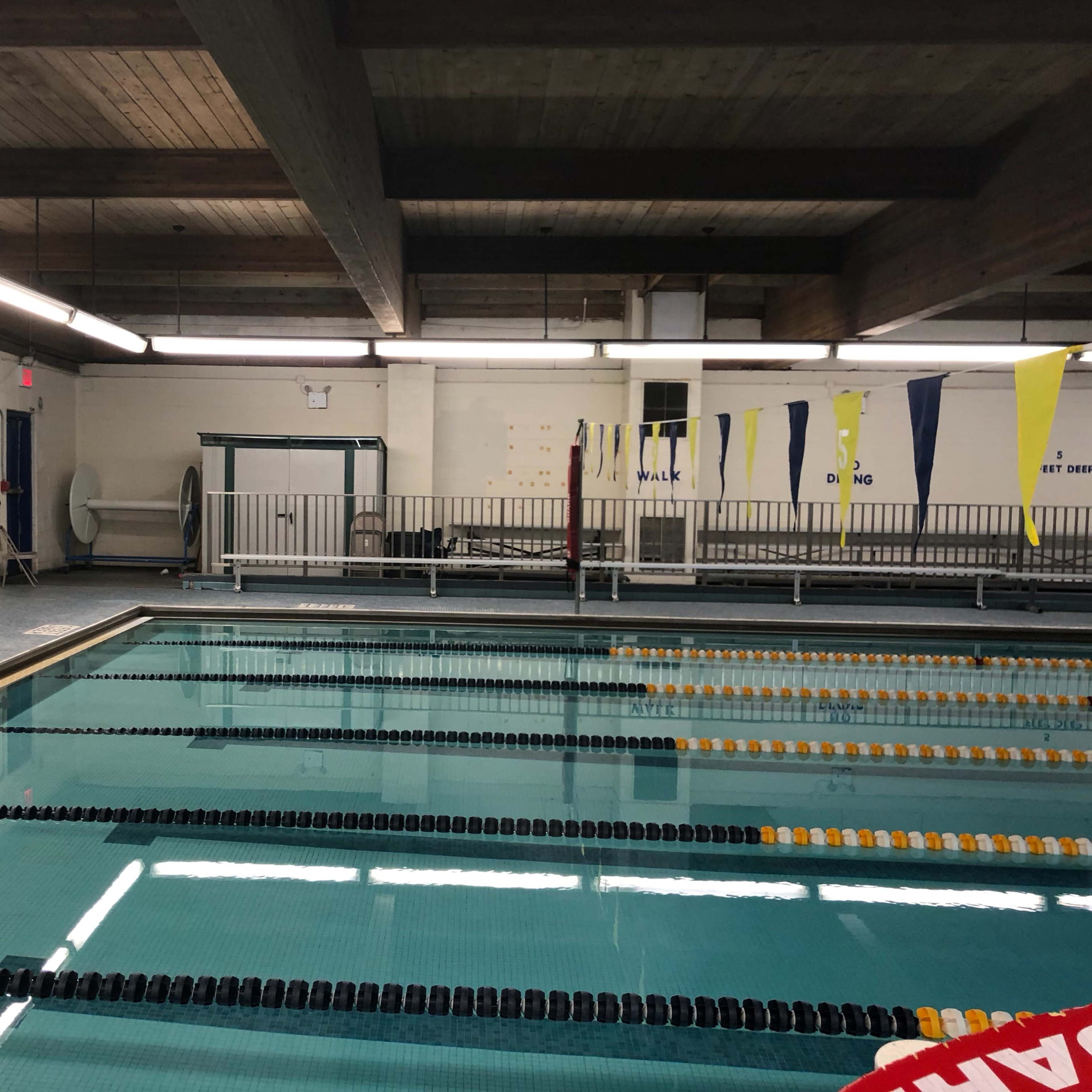 An indoor swimming pool with lane dividers and yellow and blue banners hanging along the edge.