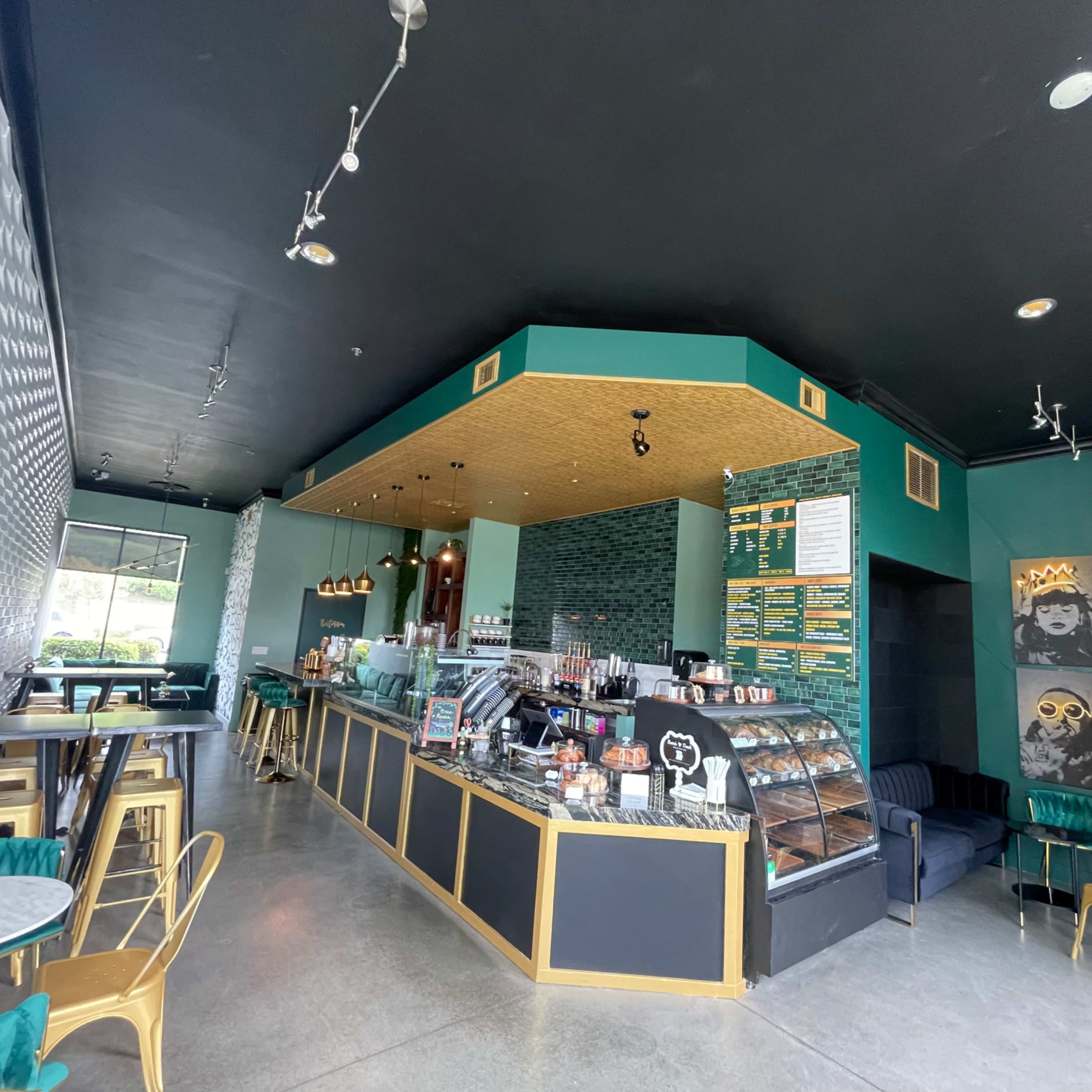 A modern café interior with a service counter, seating areas, and decorative wall art.