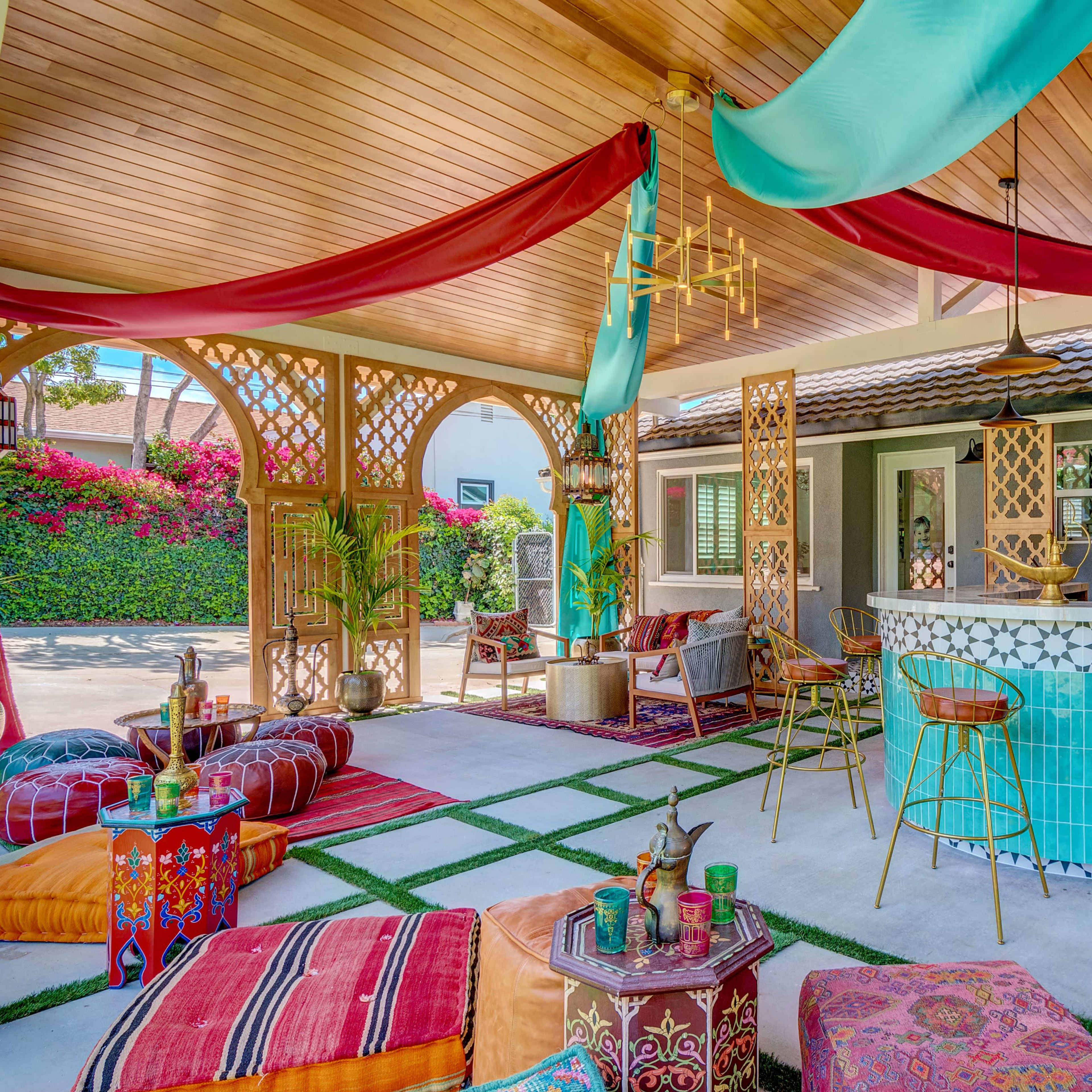 A vibrant outdoor lounge area with colorful textiles, a tiled bar, and lush greenery in the background.