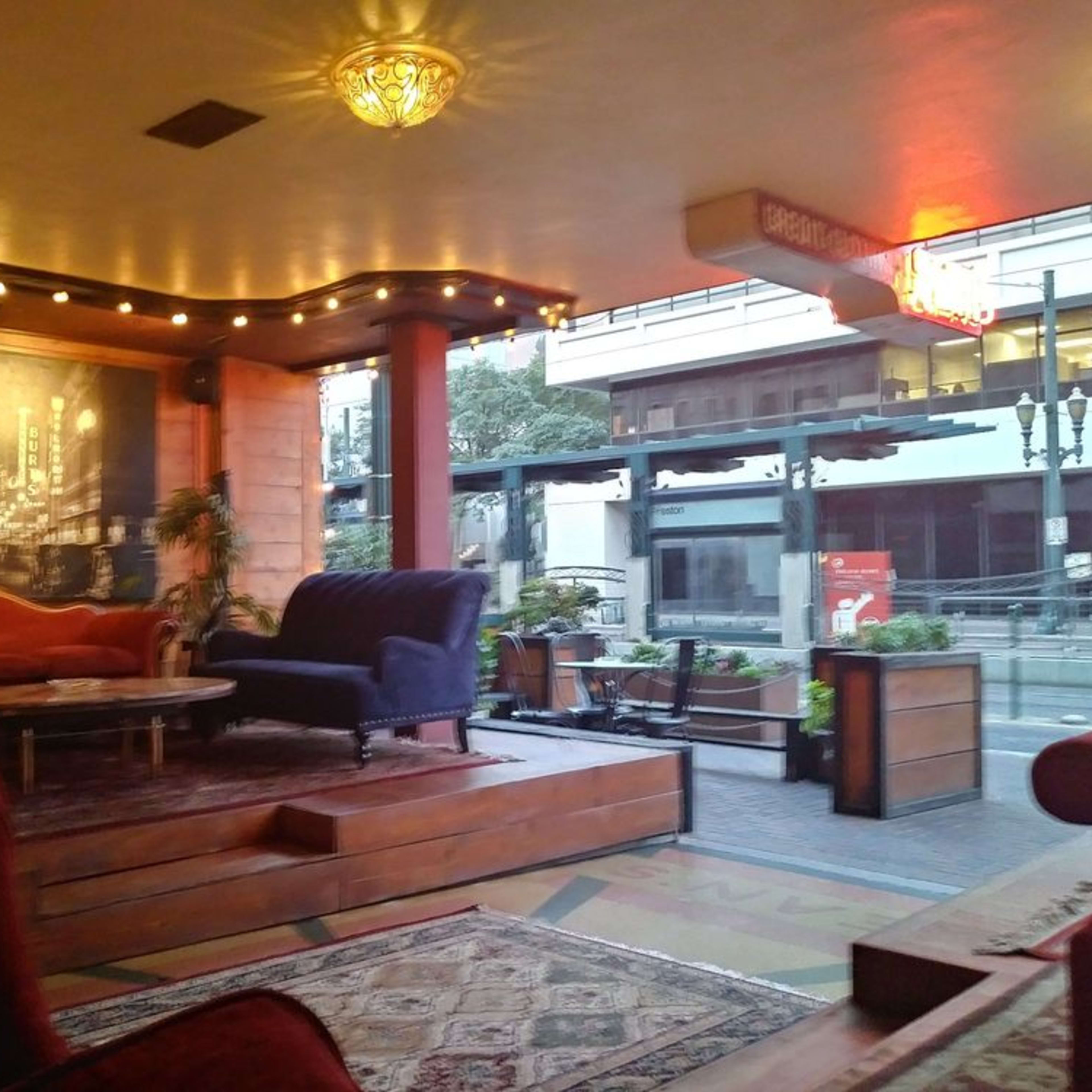 A cozy lounge area with plush seating, warm lighting, and a view of a street through large windows.