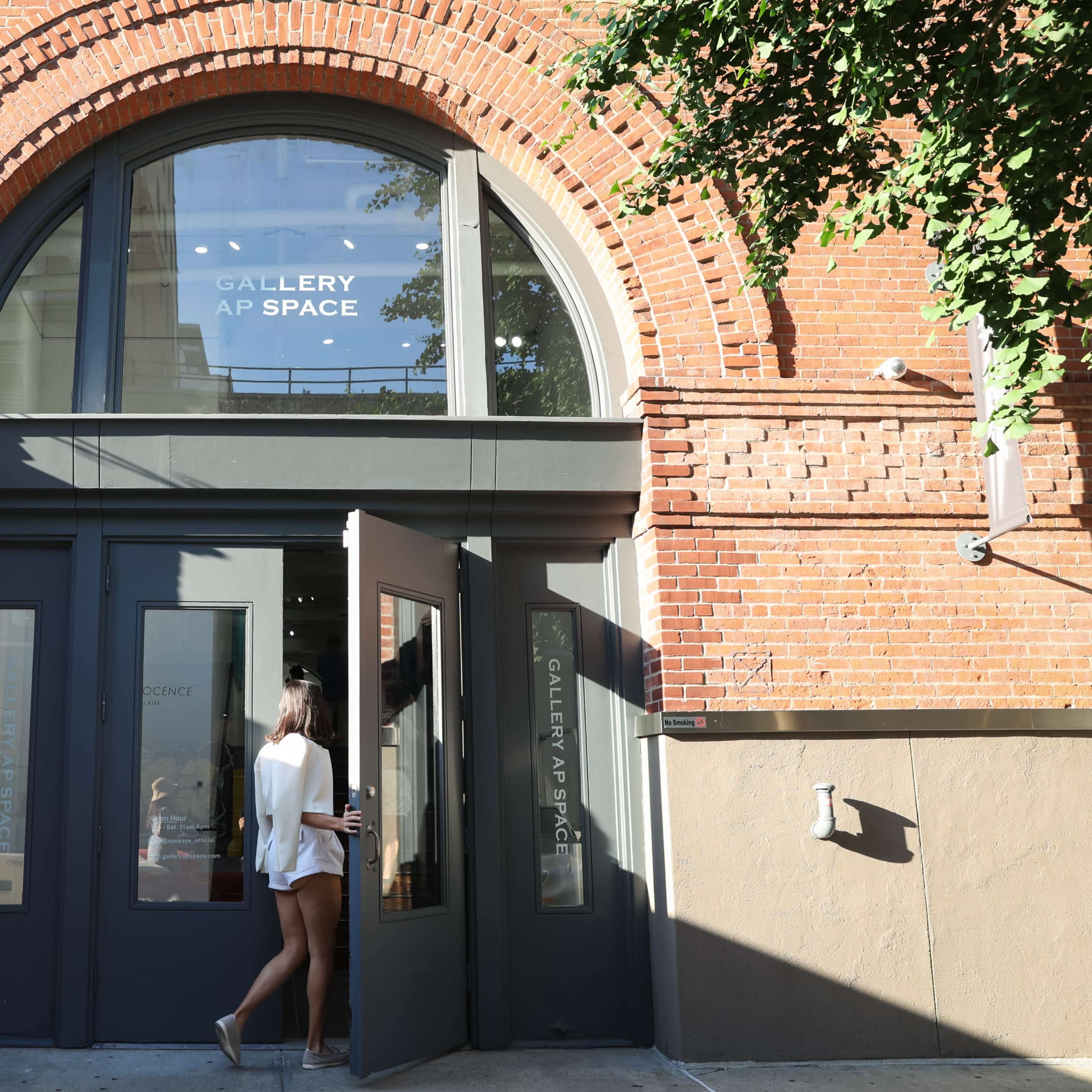 A person walks through the entrance of a brick building marked "GALLERY AP SPACE."