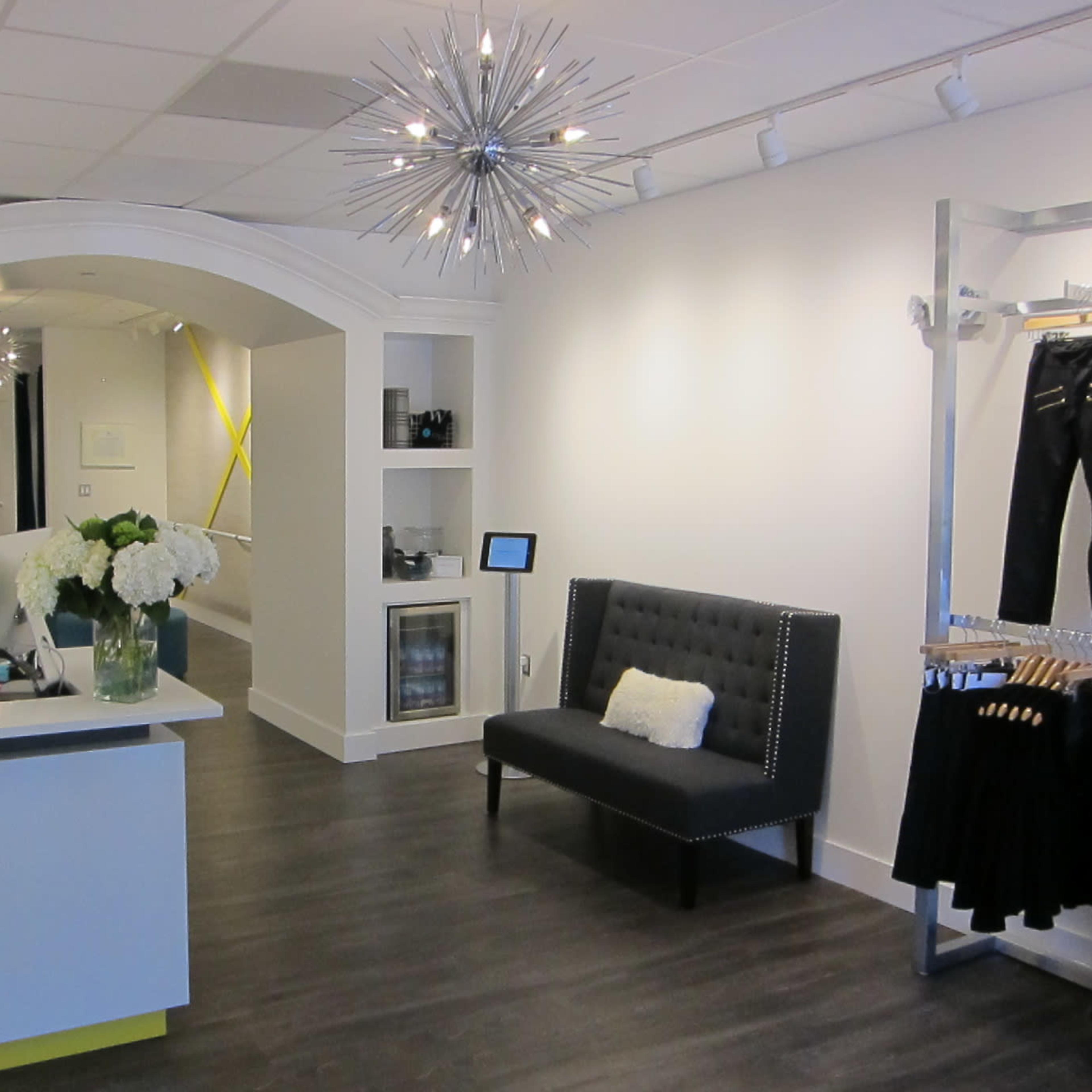 A modern retail space with a reception counter, a stylish black sofa, and a decorative light fixture overhead.