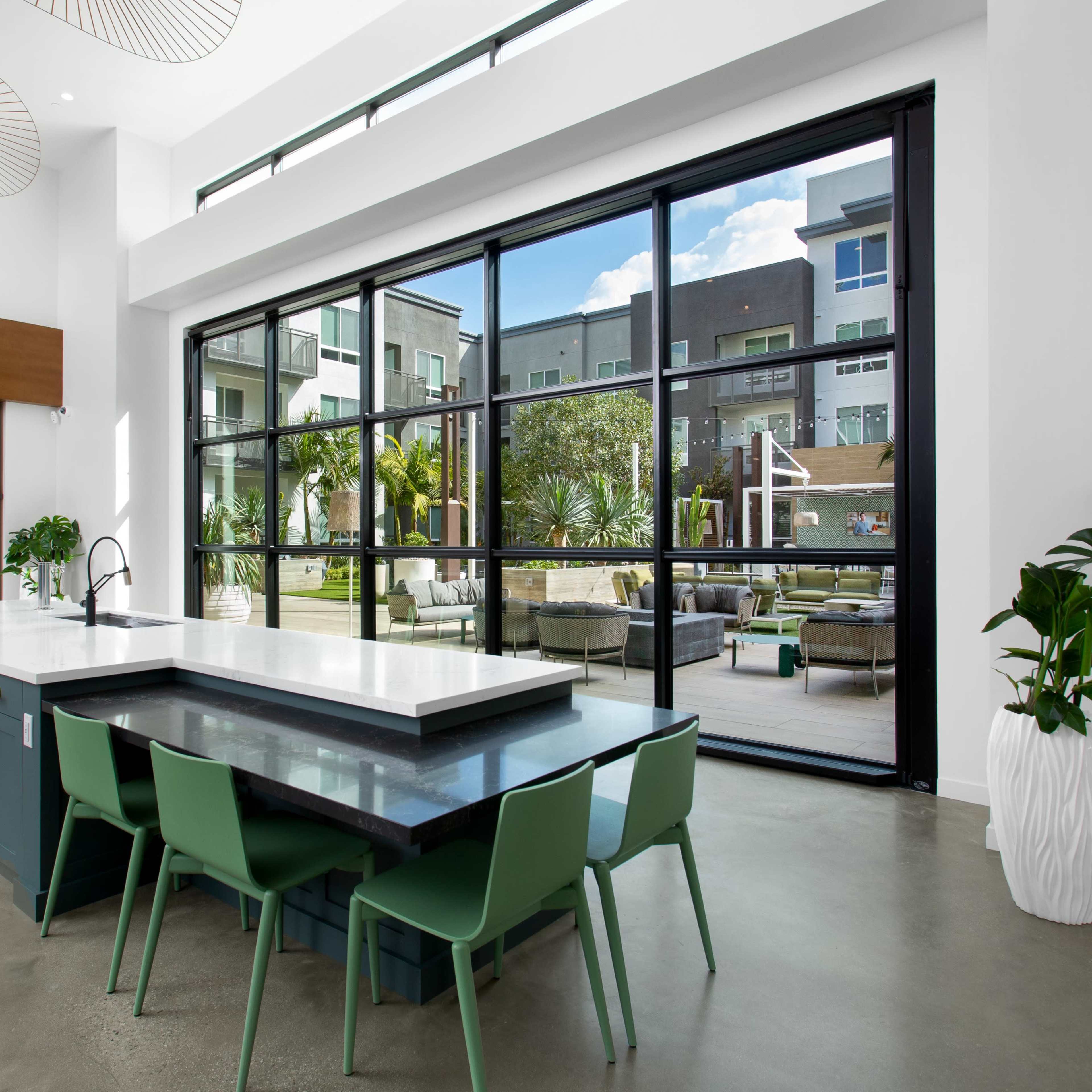 A modern kitchen features a large island with seating, overlooking a spacious outdoor area through expansive glass doors.