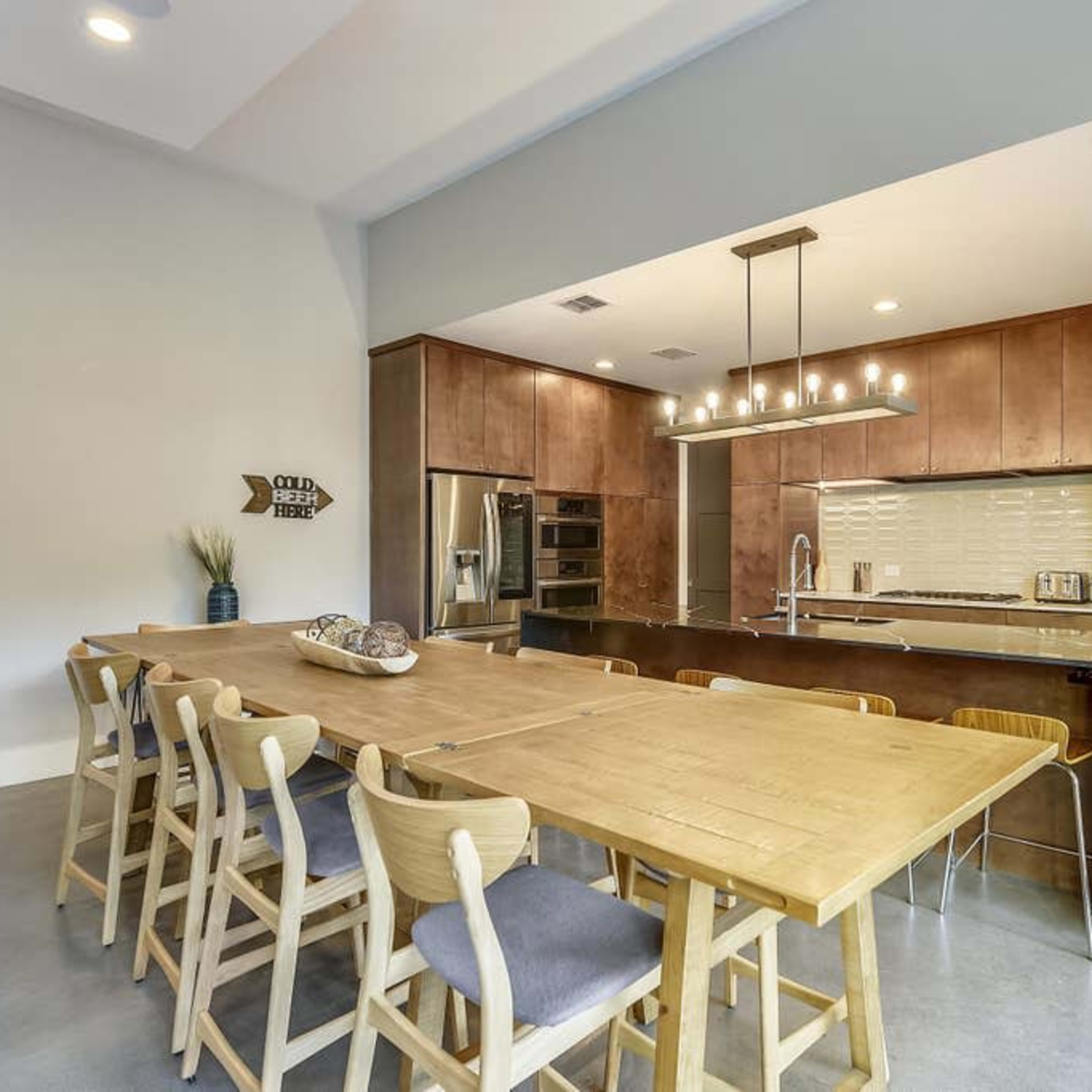 A modern kitchen and dining area with a large wooden table and contemporary cabinetry.