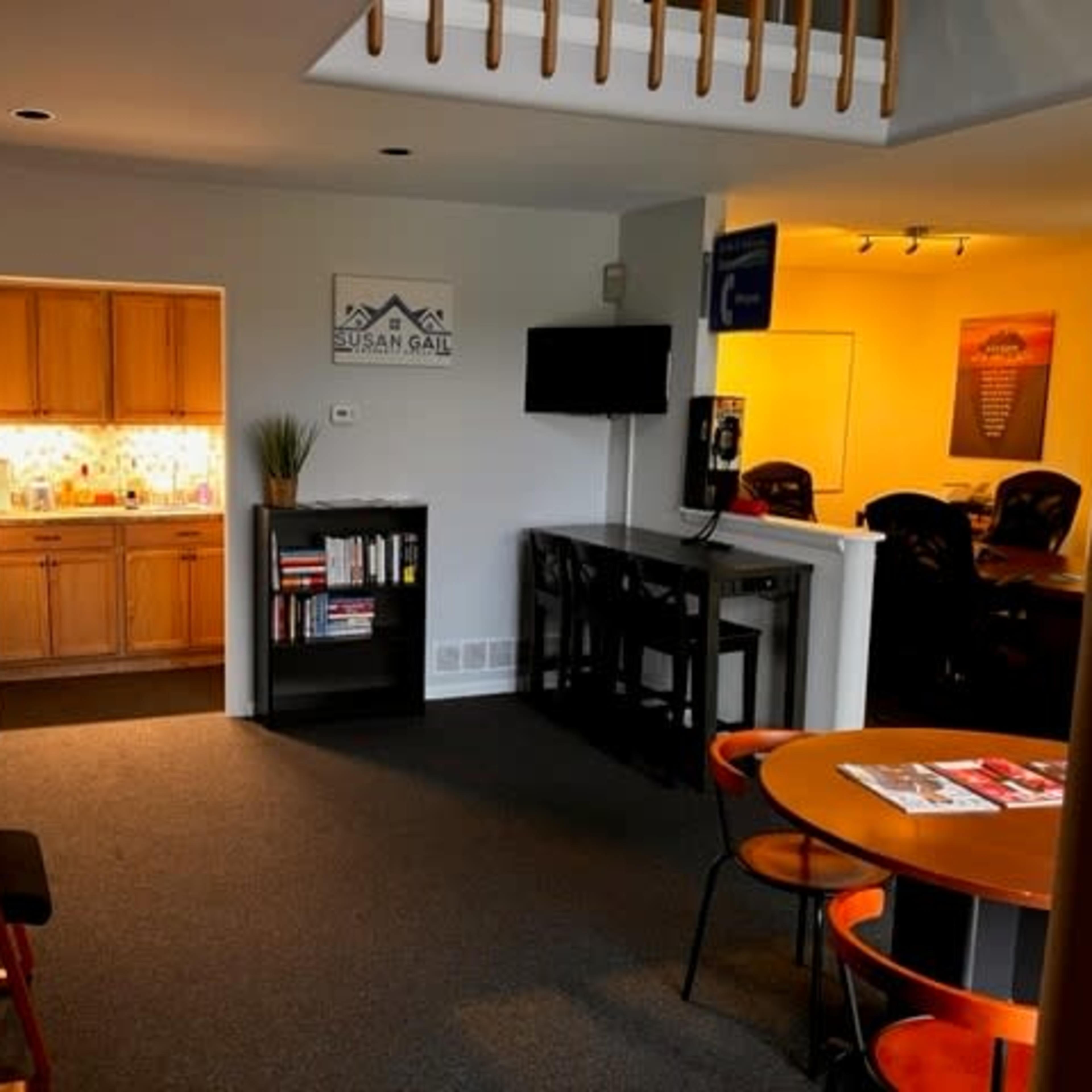 A well-lit office space with a kitchenette, bookshelves, and seating areas.