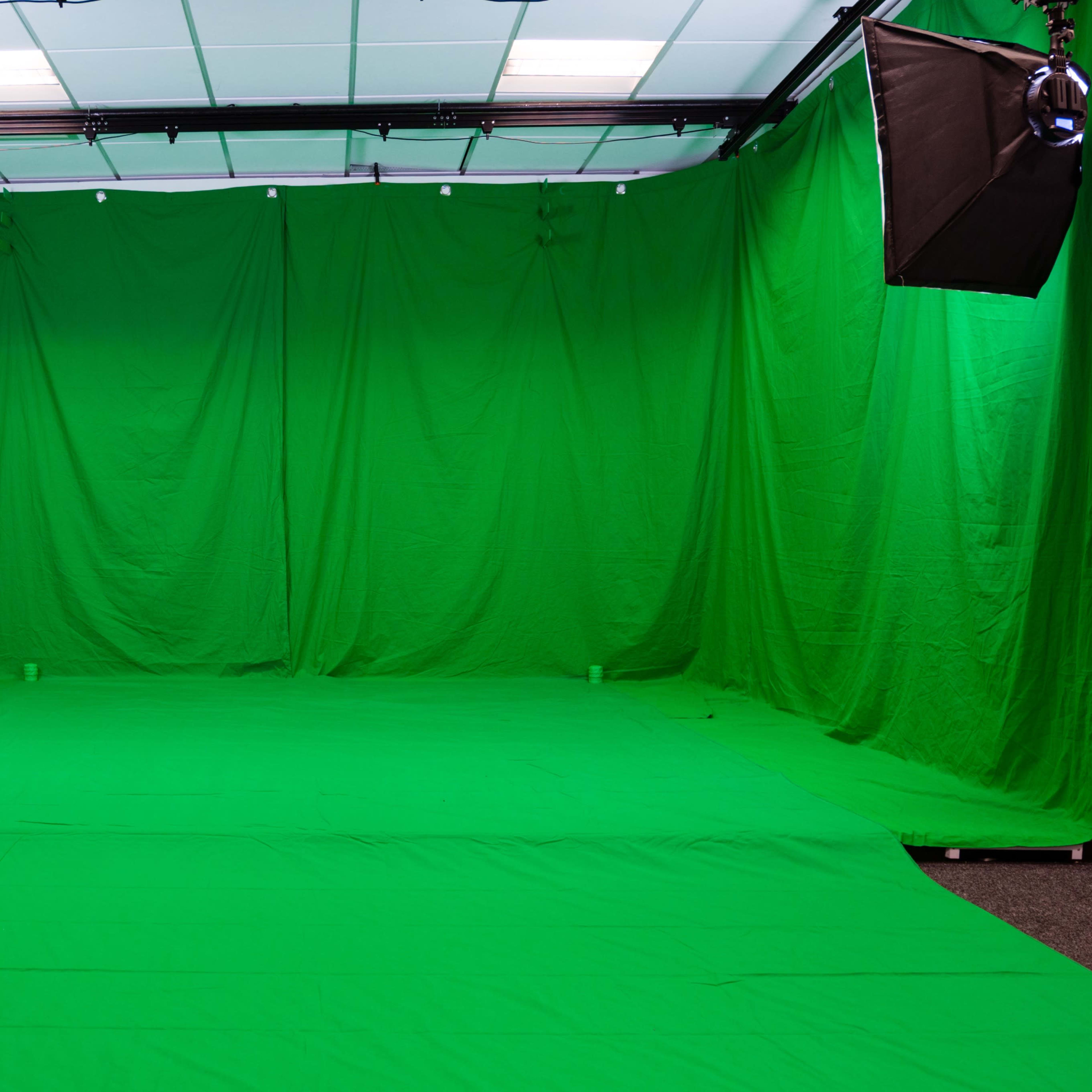 A room filled with green fabric draped on the walls and floor, set up for green screen filming.