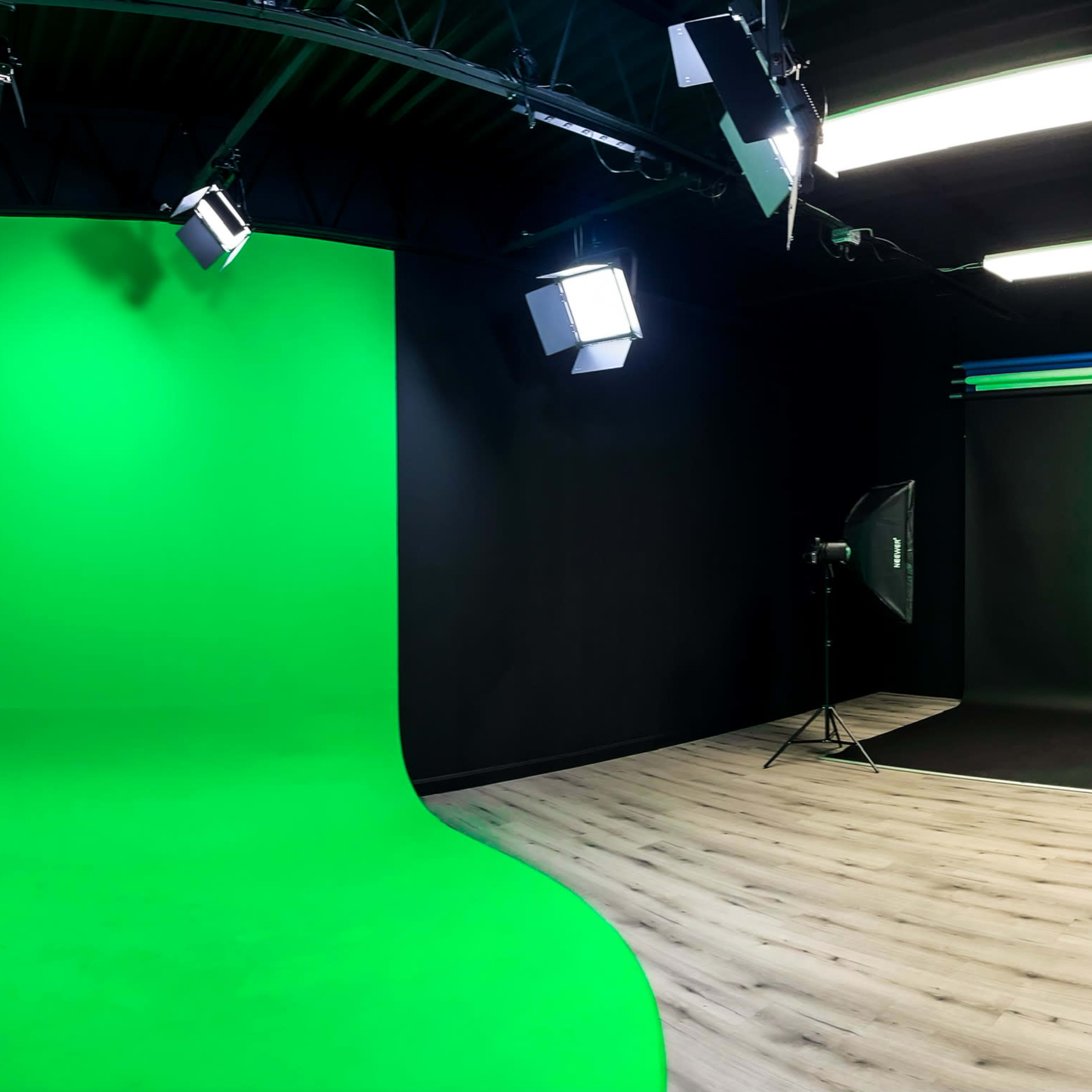 A photography studio with a green backdrop, spotlights, and a black floor.
