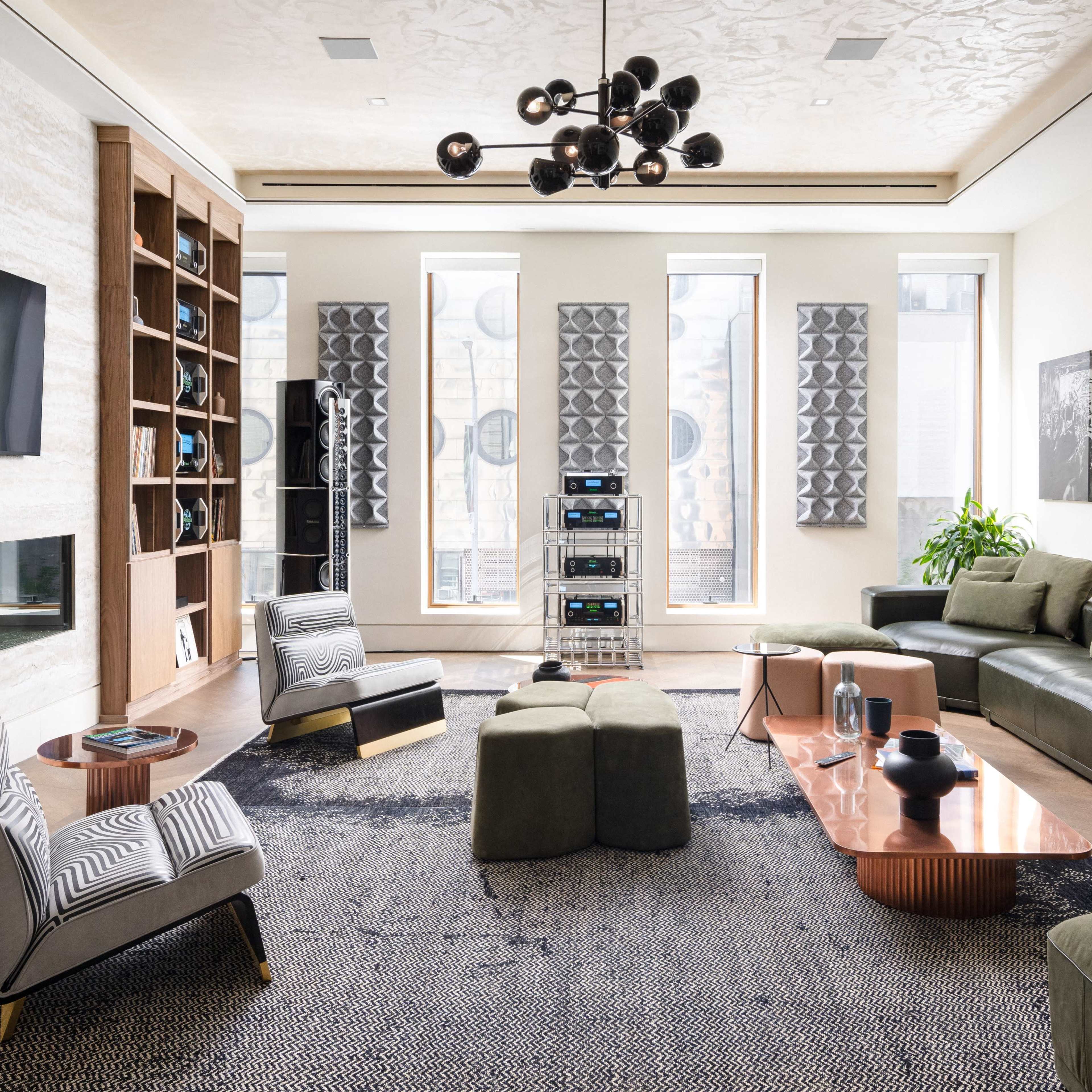 A modern living room featuring a sectional sofa, a coffee table, bookshelves, and decorative acoustic panels on the walls.
