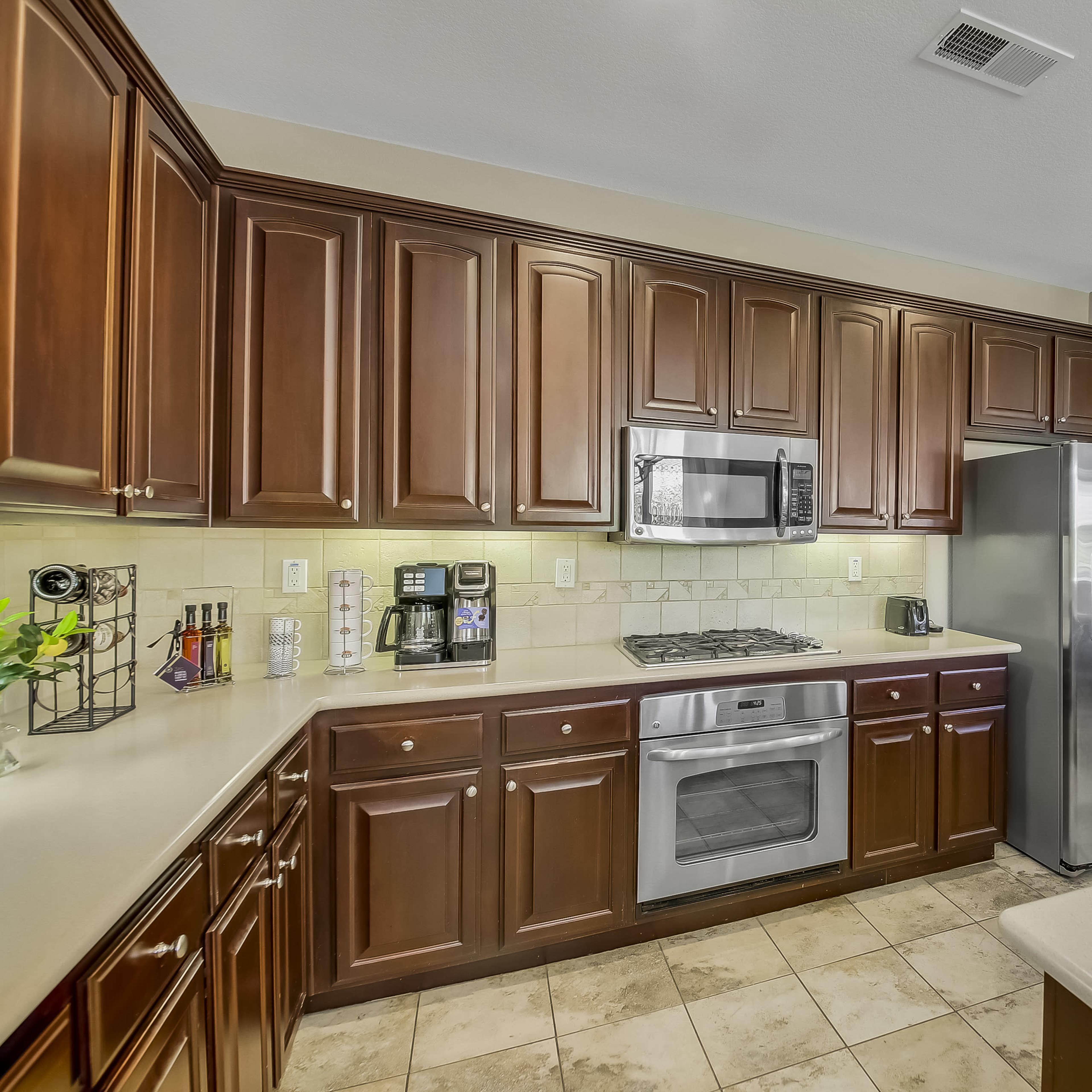 A modern kitchen with dark wooden cabinetry, stainless steel appliances, and a countertop made of light-colored material.