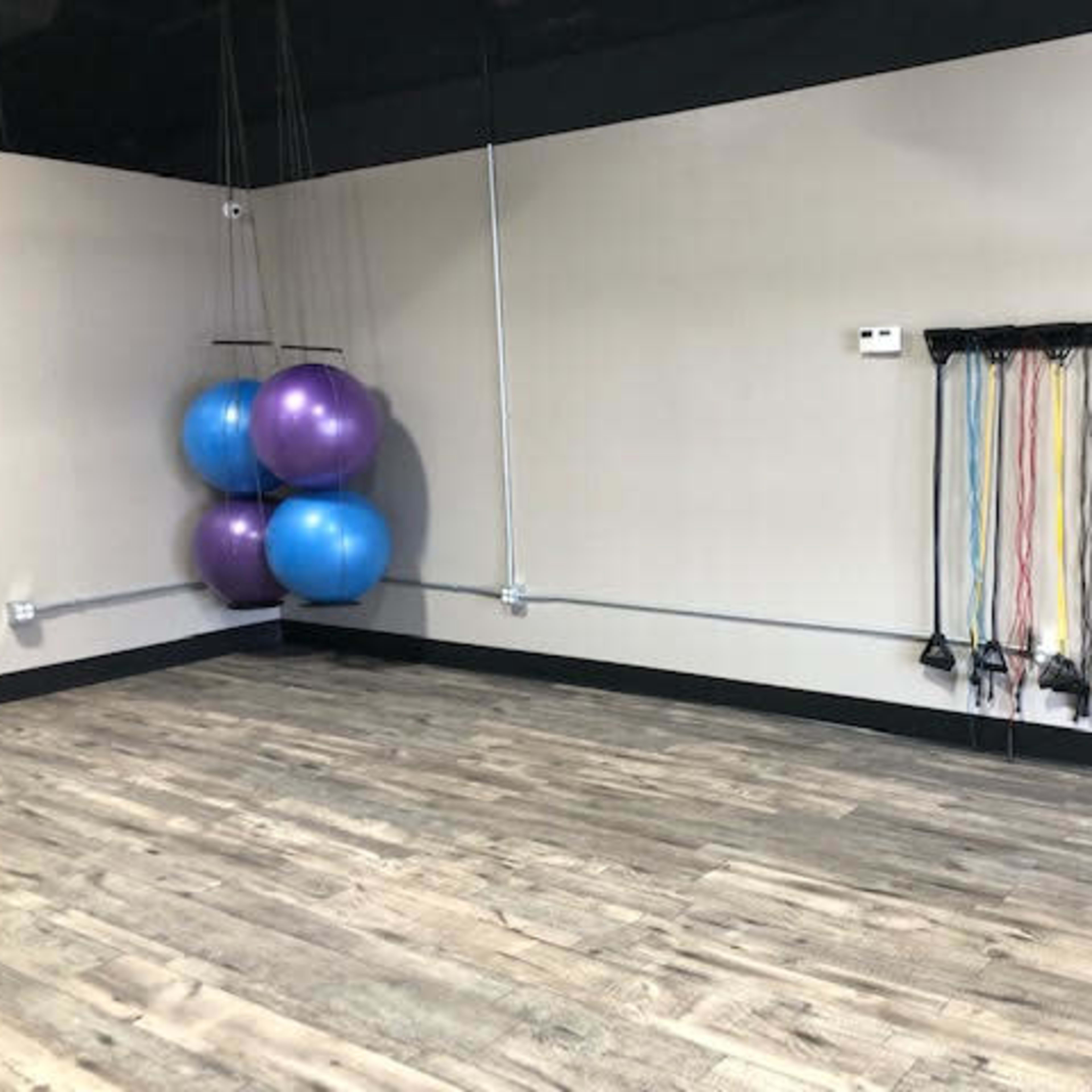 A fitness studio with two purple exercise balls and a set of resistance bands mounted on the wall.