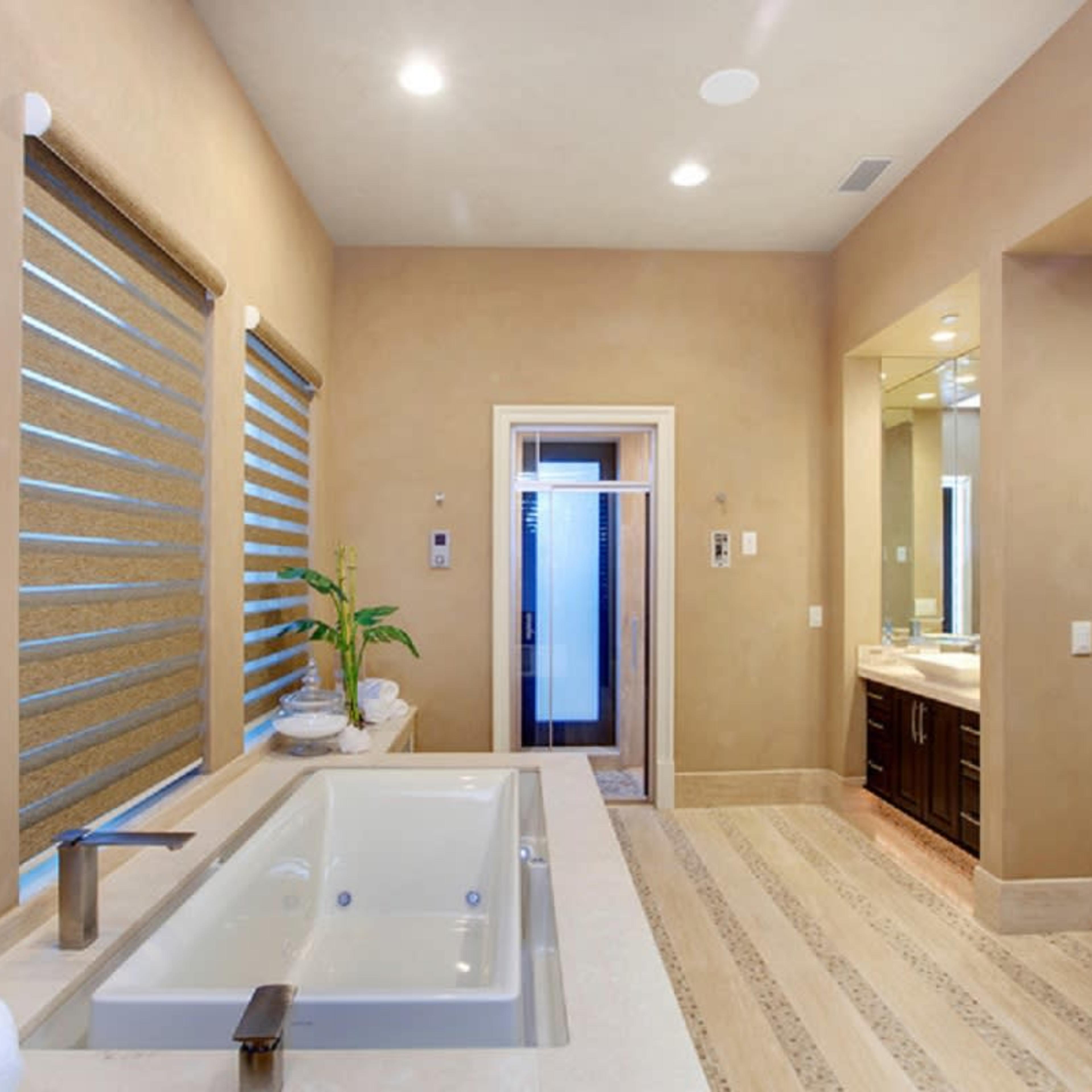 A modern bathroom with a freestanding bathtub, wooden window shades, and a double vanity with a mirror.