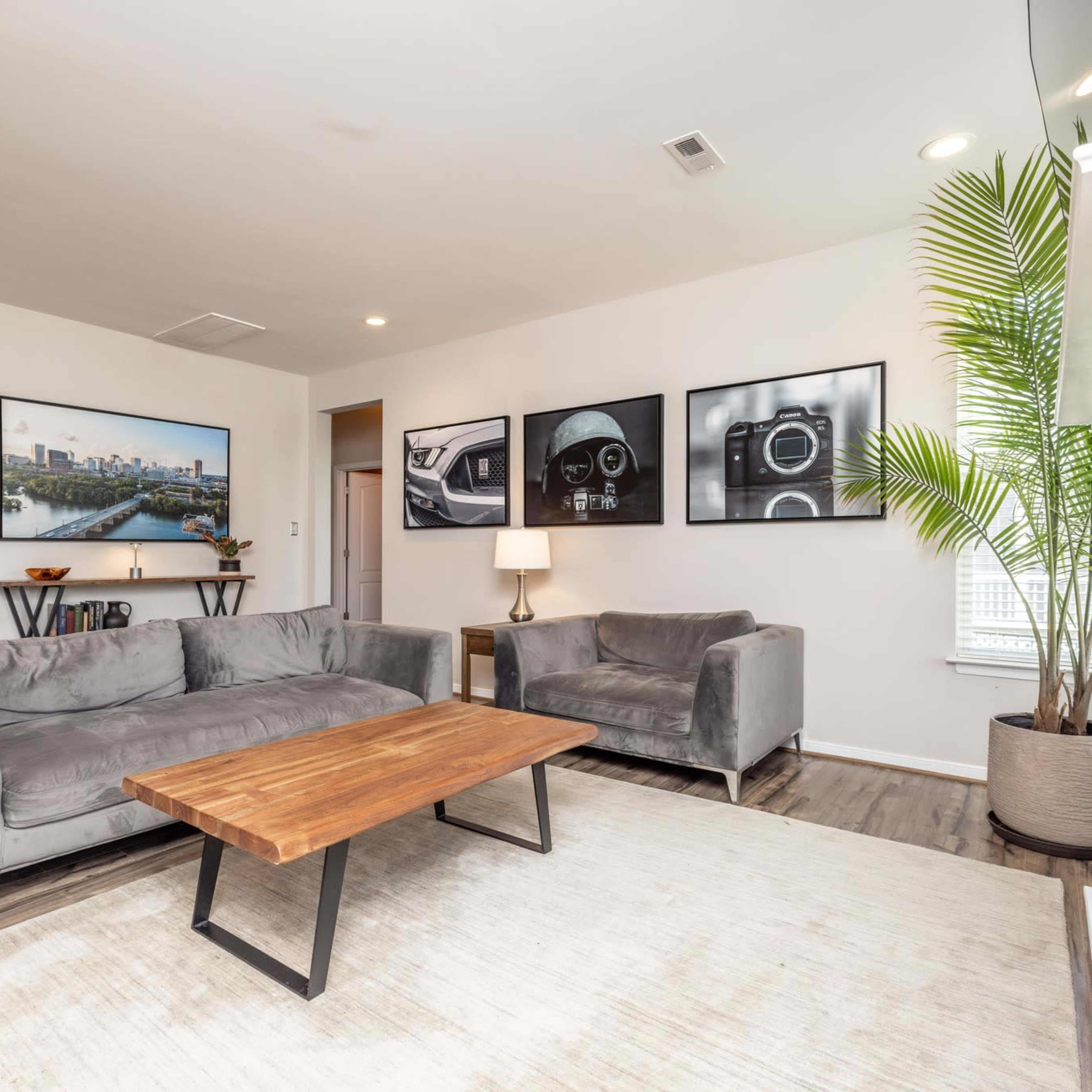 A modern living room with gray sofas, a wooden coffee table, and framed black-and-white photographs on the walls.
