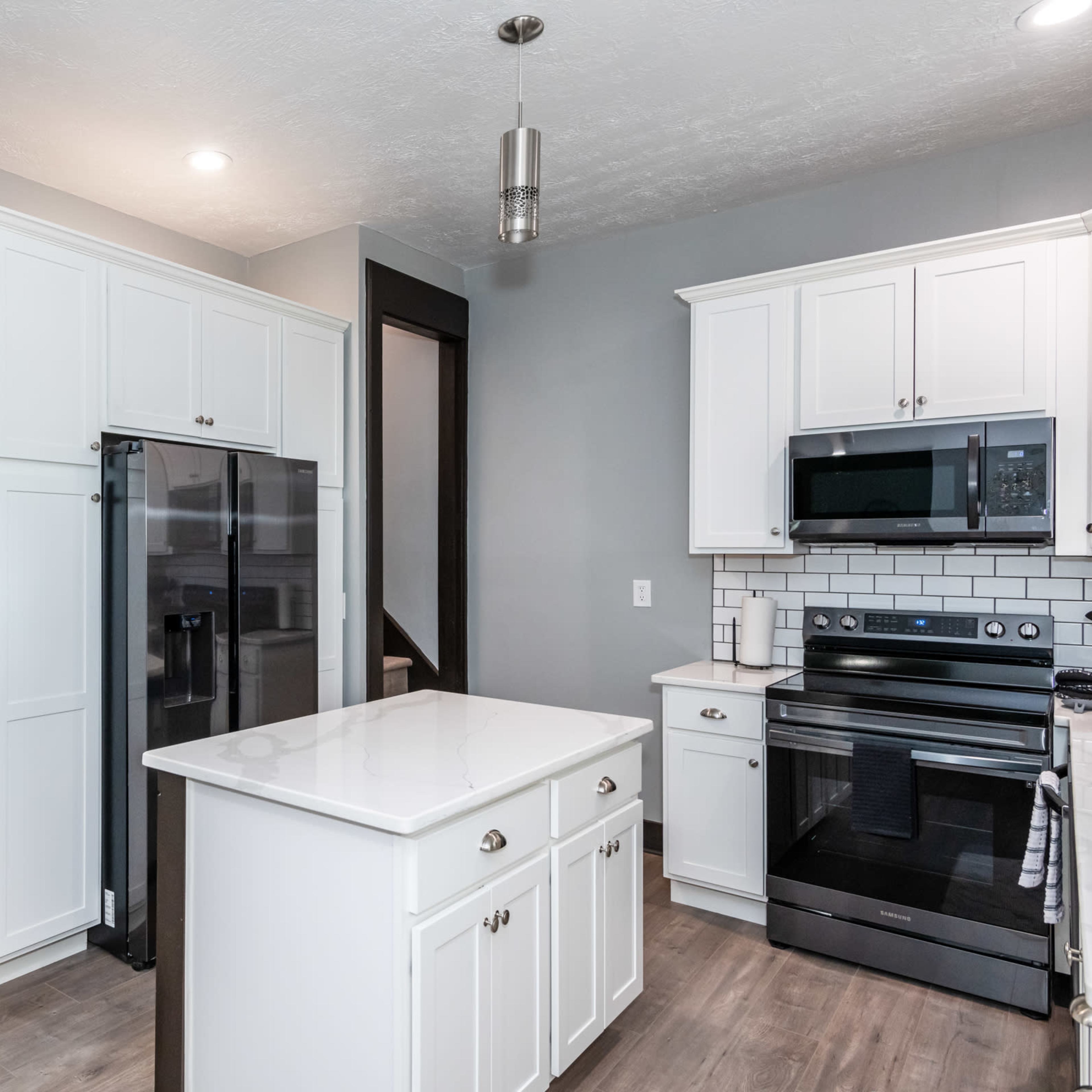 A modern kitchen featuring white cabinetry, stainless steel appliances, and a central island.