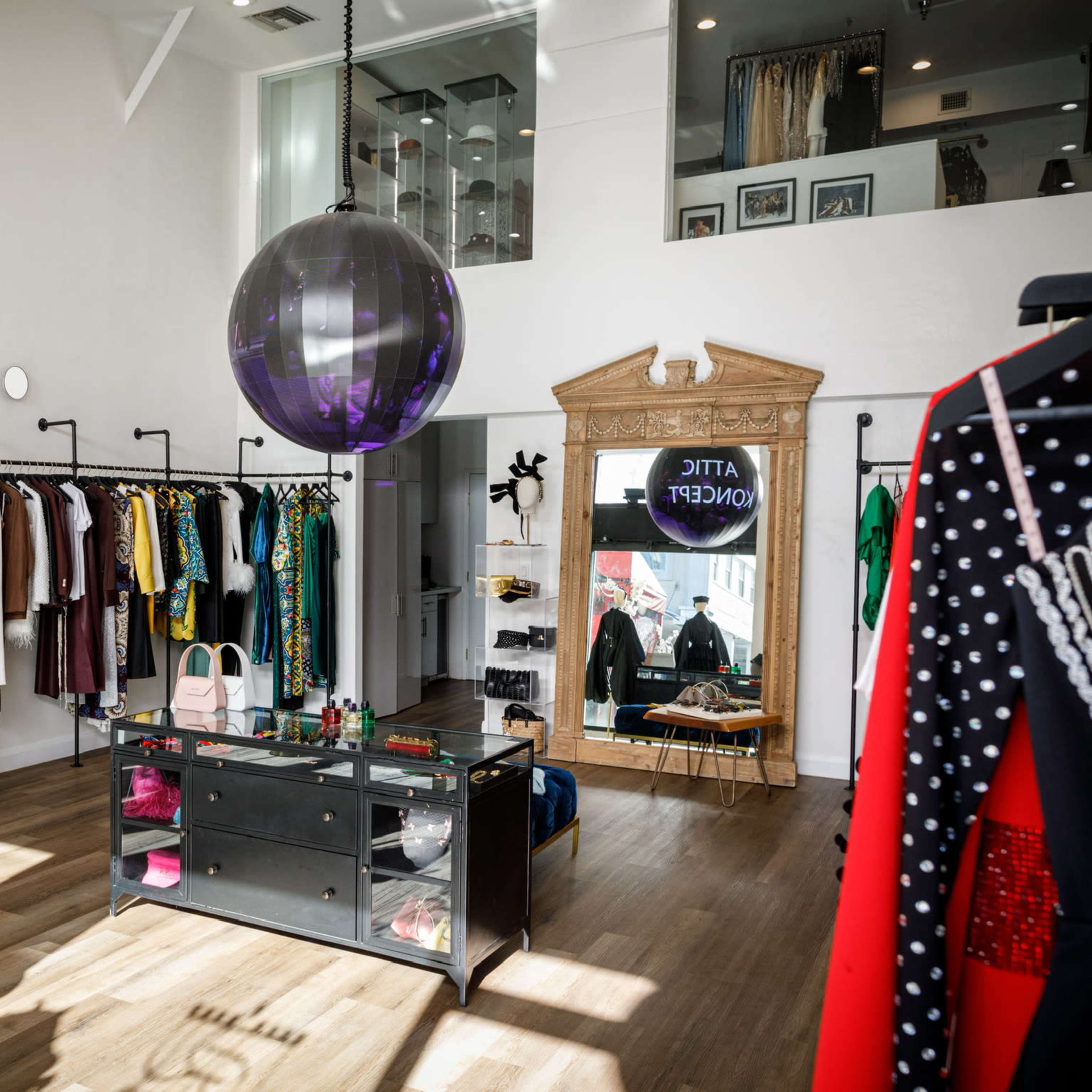 A stylish clothing boutique with racks of colorful garments lining the walls and a central display table featuring accessories.