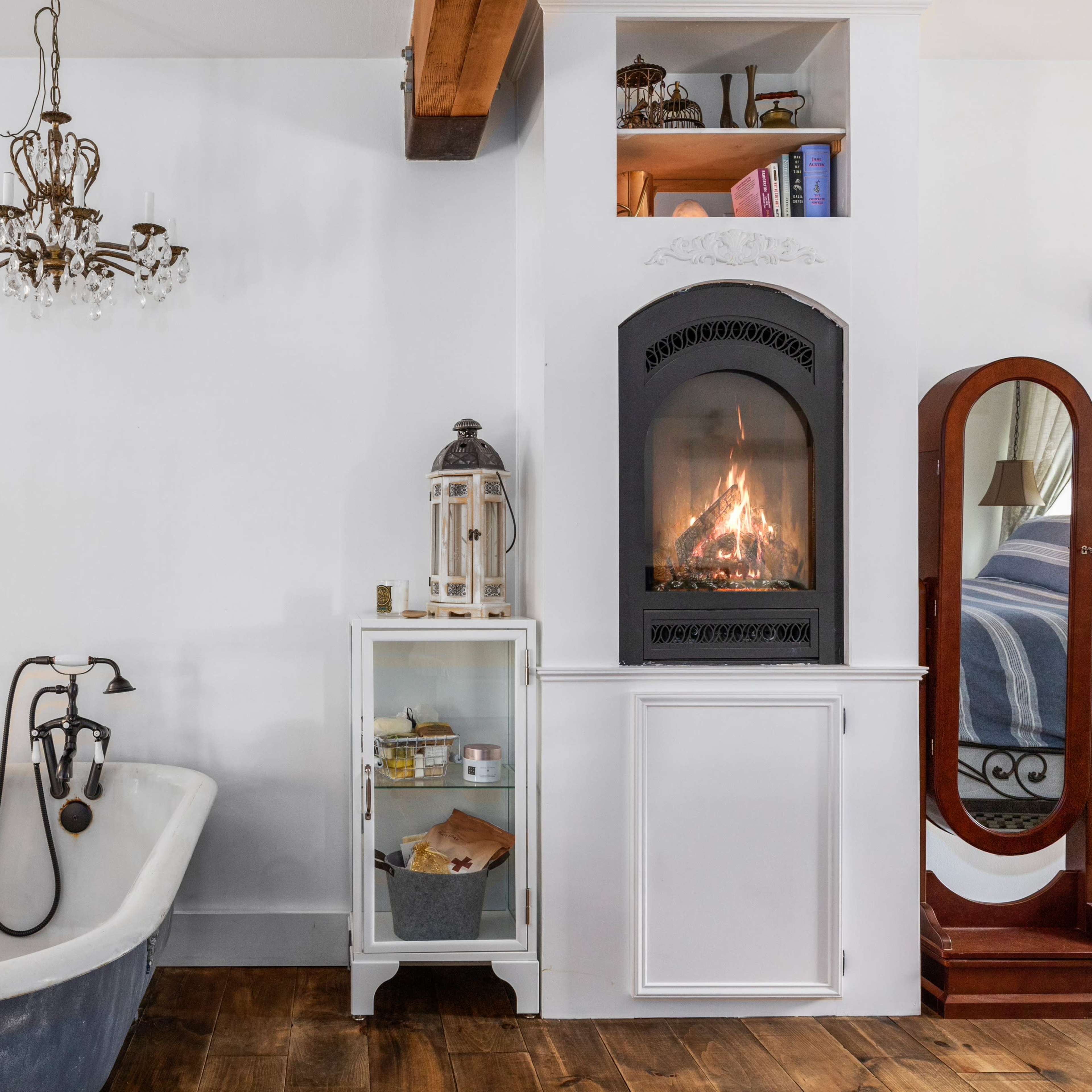 A bathroom featuring a freestanding bathtub, a fireplace built into the cabinetry, and a chandelier hanging from the ceiling.