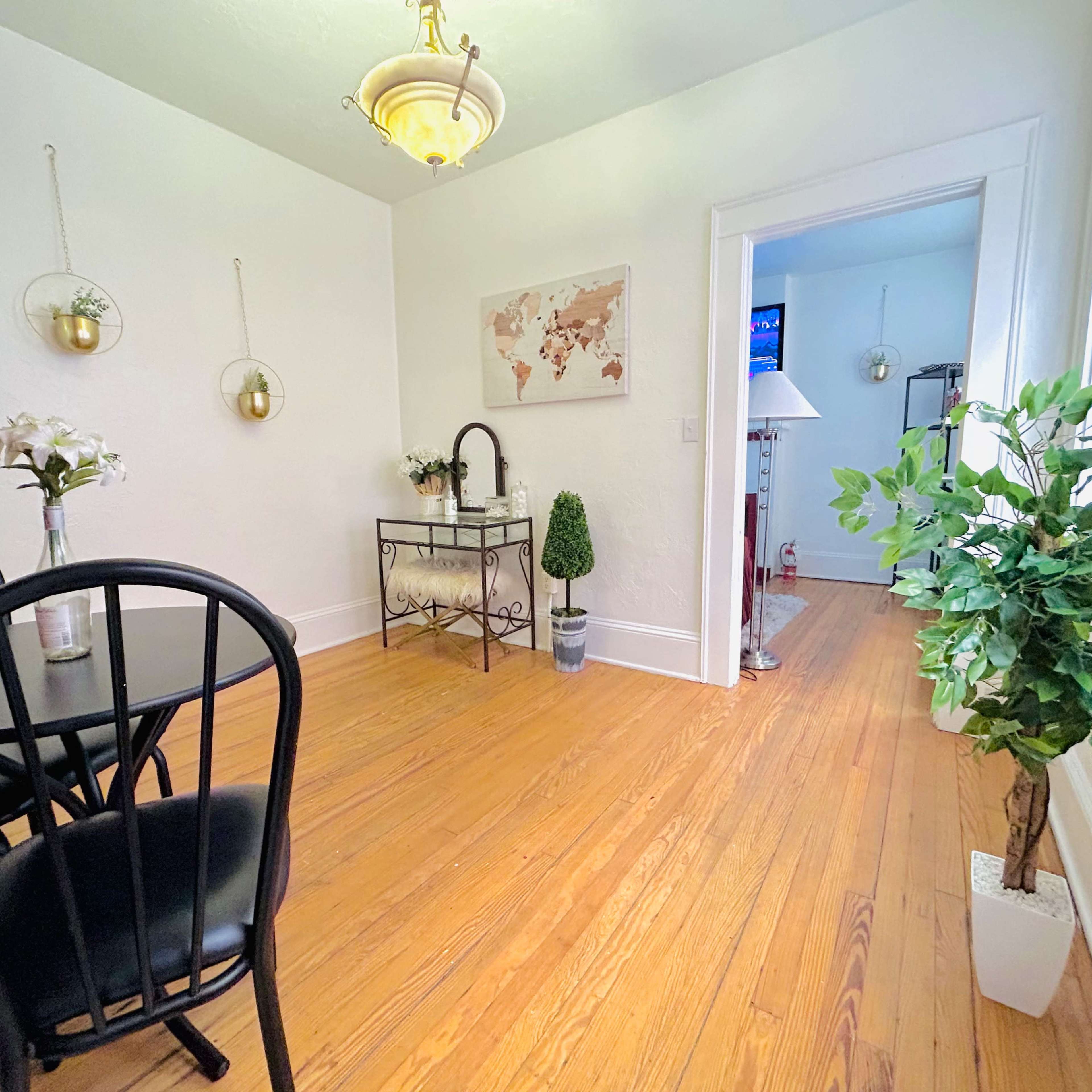 A bright, neatly arranged dining space featuring a black table and chairs, a decorative map on the wall, and potted plants.