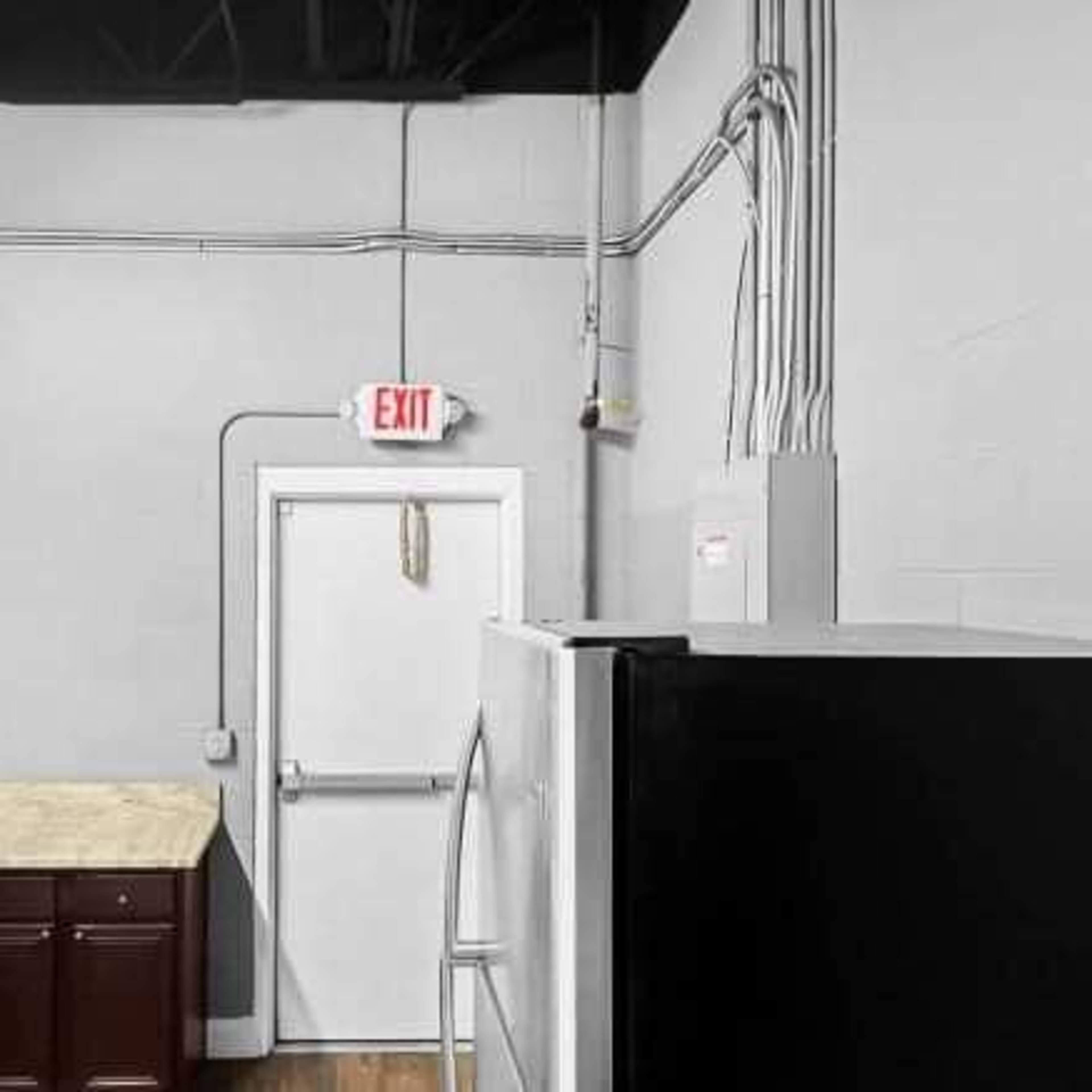 A kitchen with dark cabinetry, a stainless steel refrigerator, and electrical wiring along the walls.