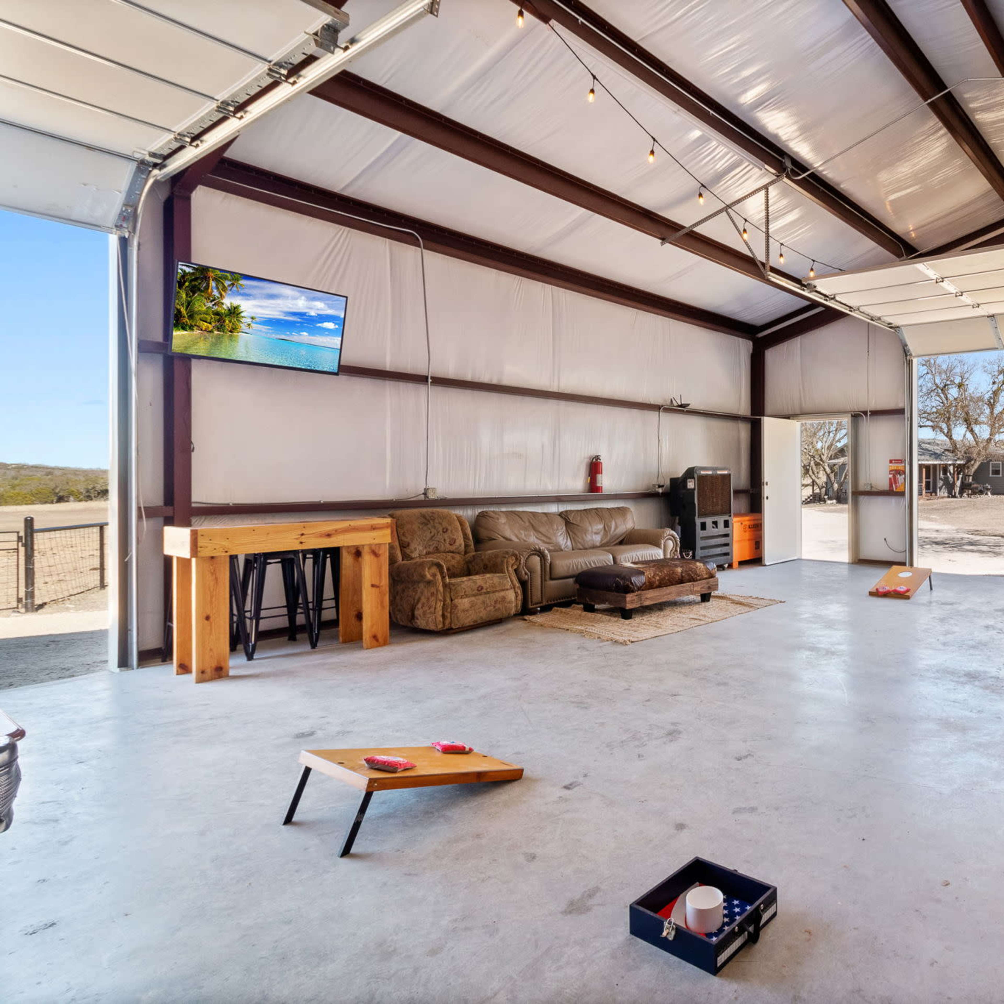A spacious garage with a seating area, a television, and a few game boards on the floor.
