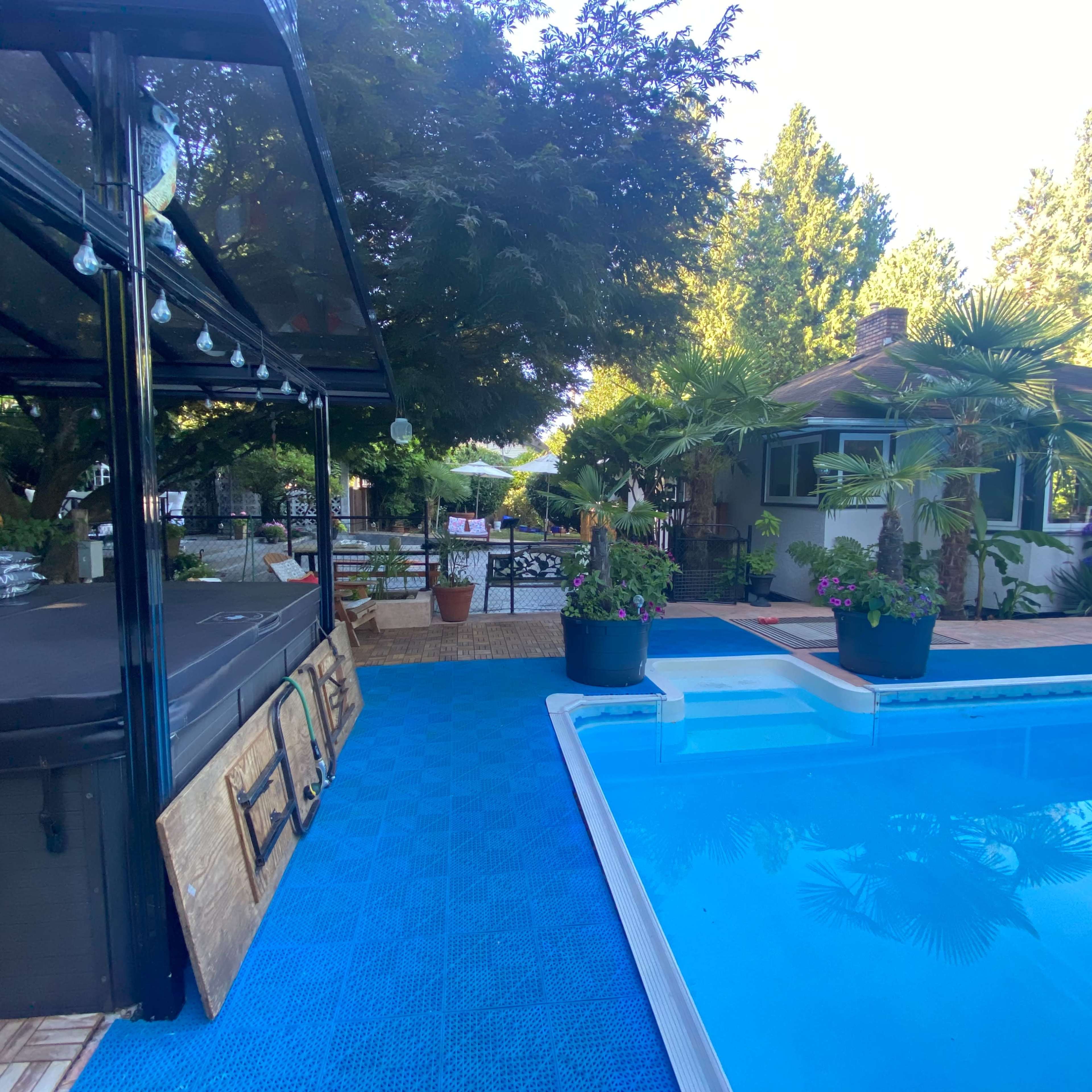 A poolside area with a covered seating space and surrounding greenery.