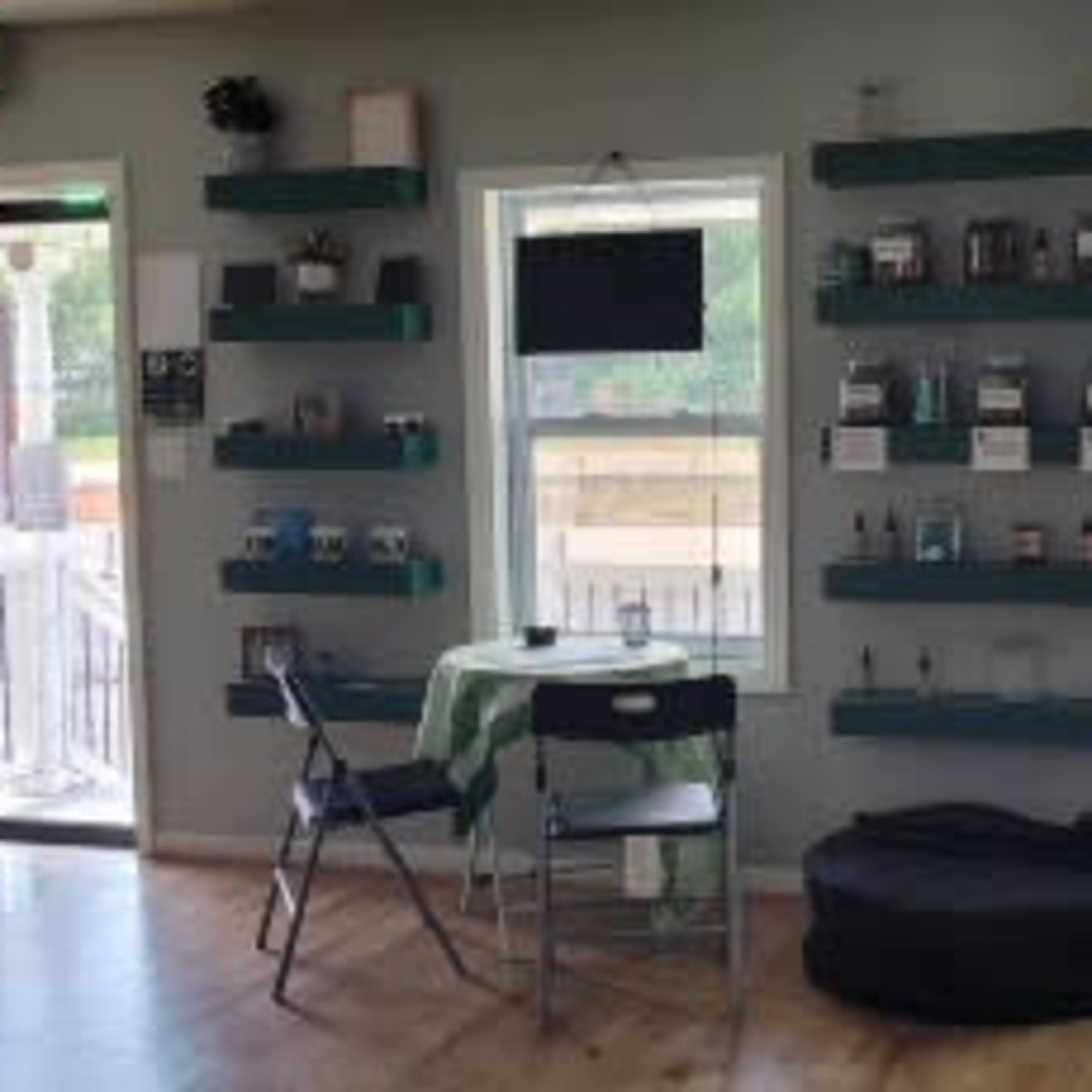 The interior of a CBD shop features shelves displaying products, a table with chairs, and a large door leading outside.